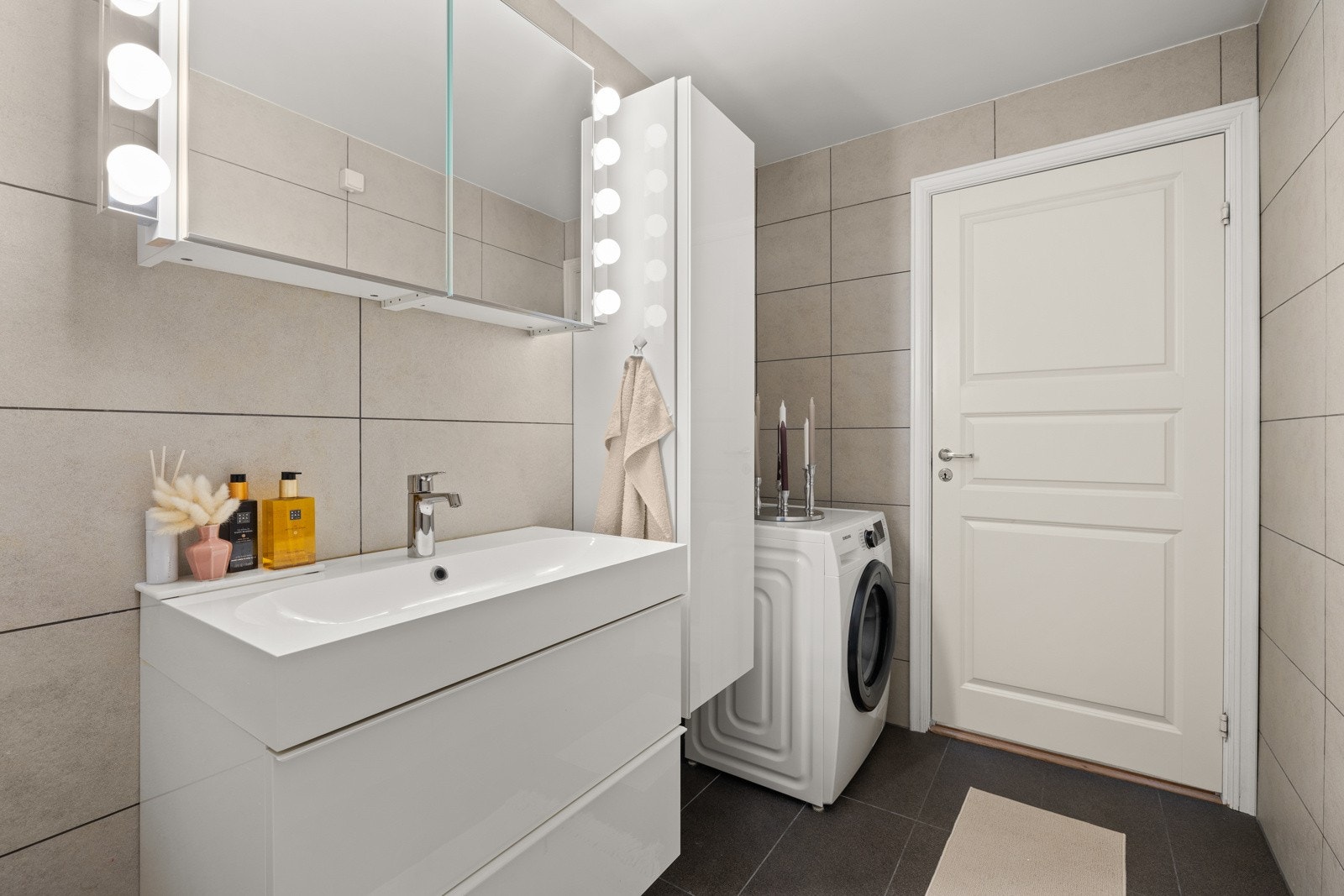 Baderomsinnredning med glatte skapfronter i hvit høyglans. Opplegg for vaskemaskin. Galleribilde