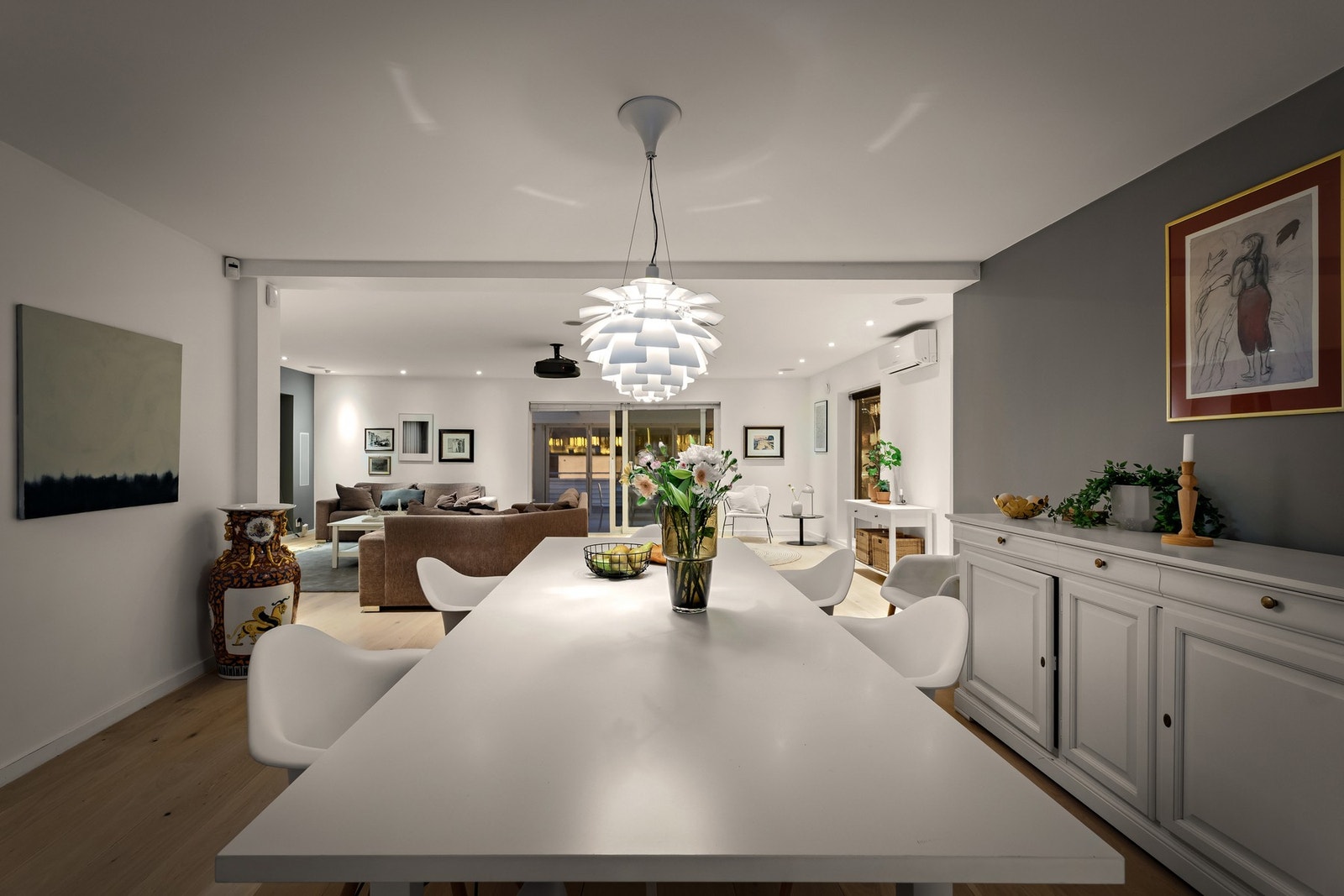 Lyst og romslig oppholdsrom med åpen løsning mellom spiseplass og stue, samt god belysning og moderne innredning. Galleribilde