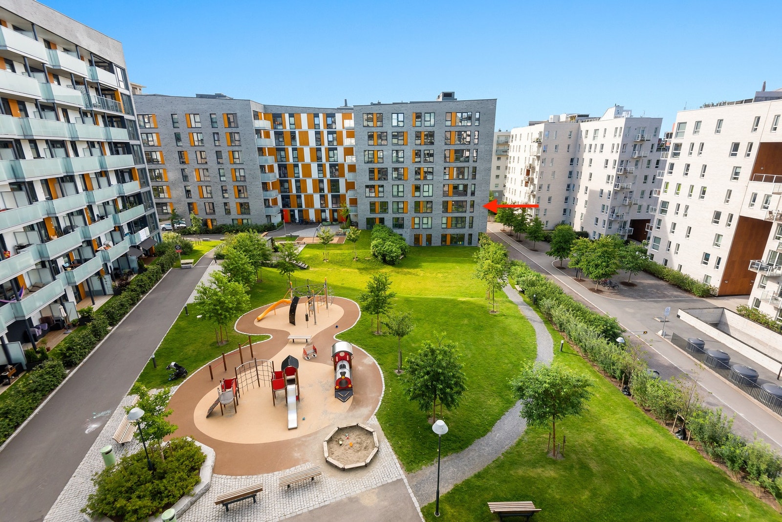 Leiligheten ligger i en høy 2. etasje på hjørnet av bygget (markert med rød pil). Dette er i realiteten en 3. etasje, siden leiligheten vender mot en skråning. Galleribilde