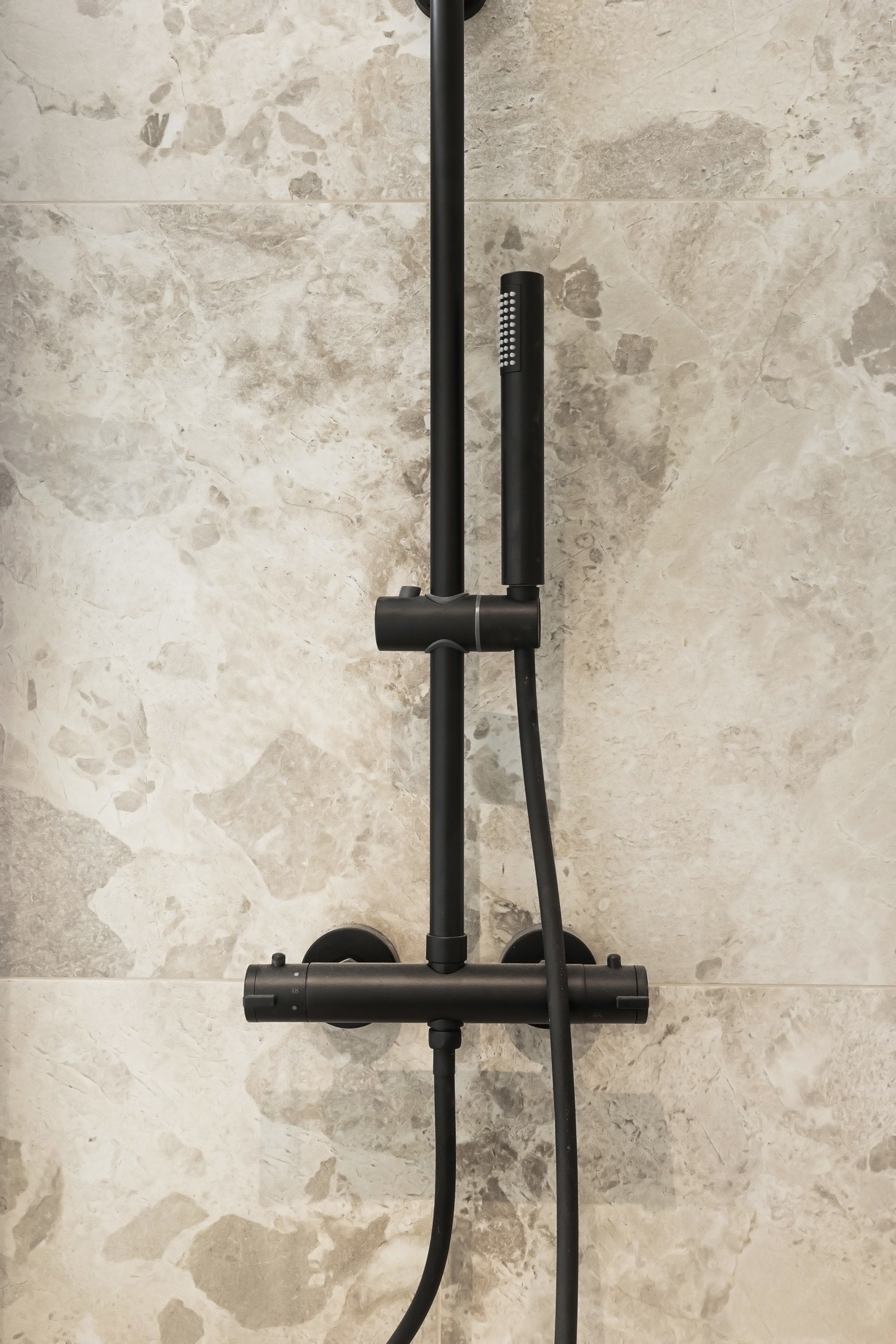 Lekre baderomsfliser i dusjsonen med sort regnfallsdusj. Galleribilde