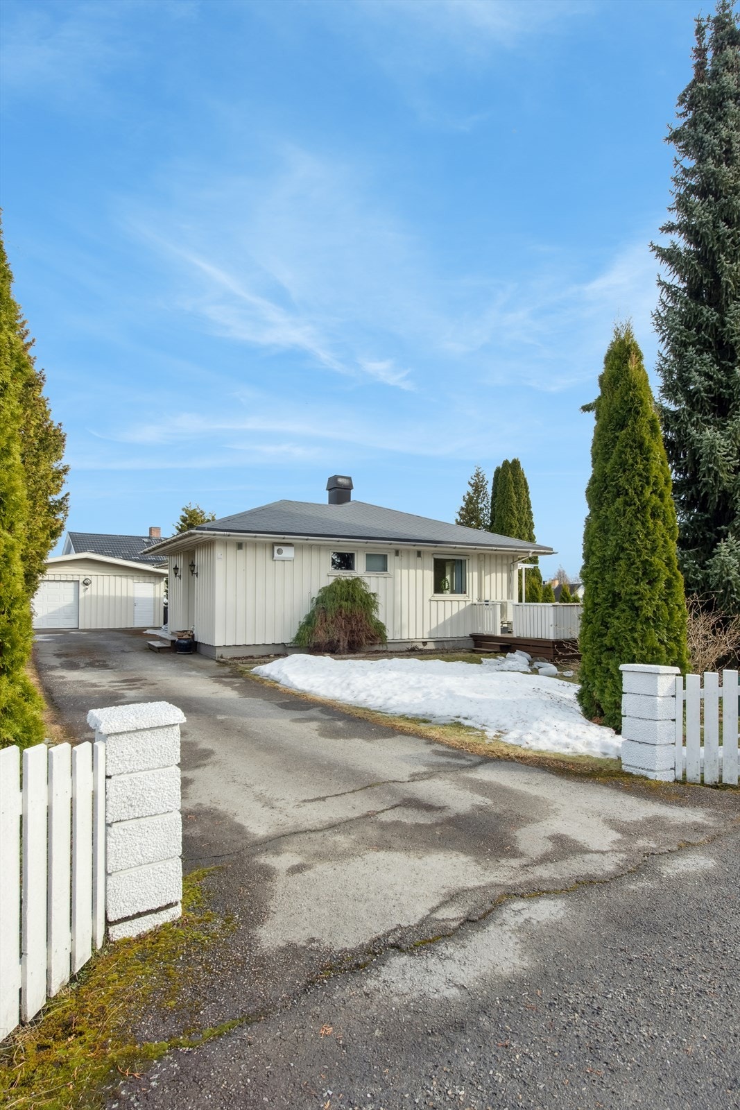 Pent opparbeidet tomt med gjerde, asfalt, plenarealer med prydbusker og trær. Galleribilde