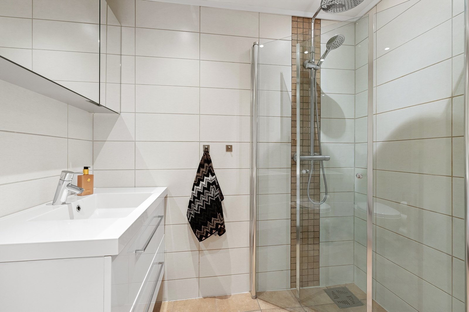 Rommet har dusjnisje, vegghengt klosett, godt med lagringsplass i speilskap og servantskuffer. Galleribilde