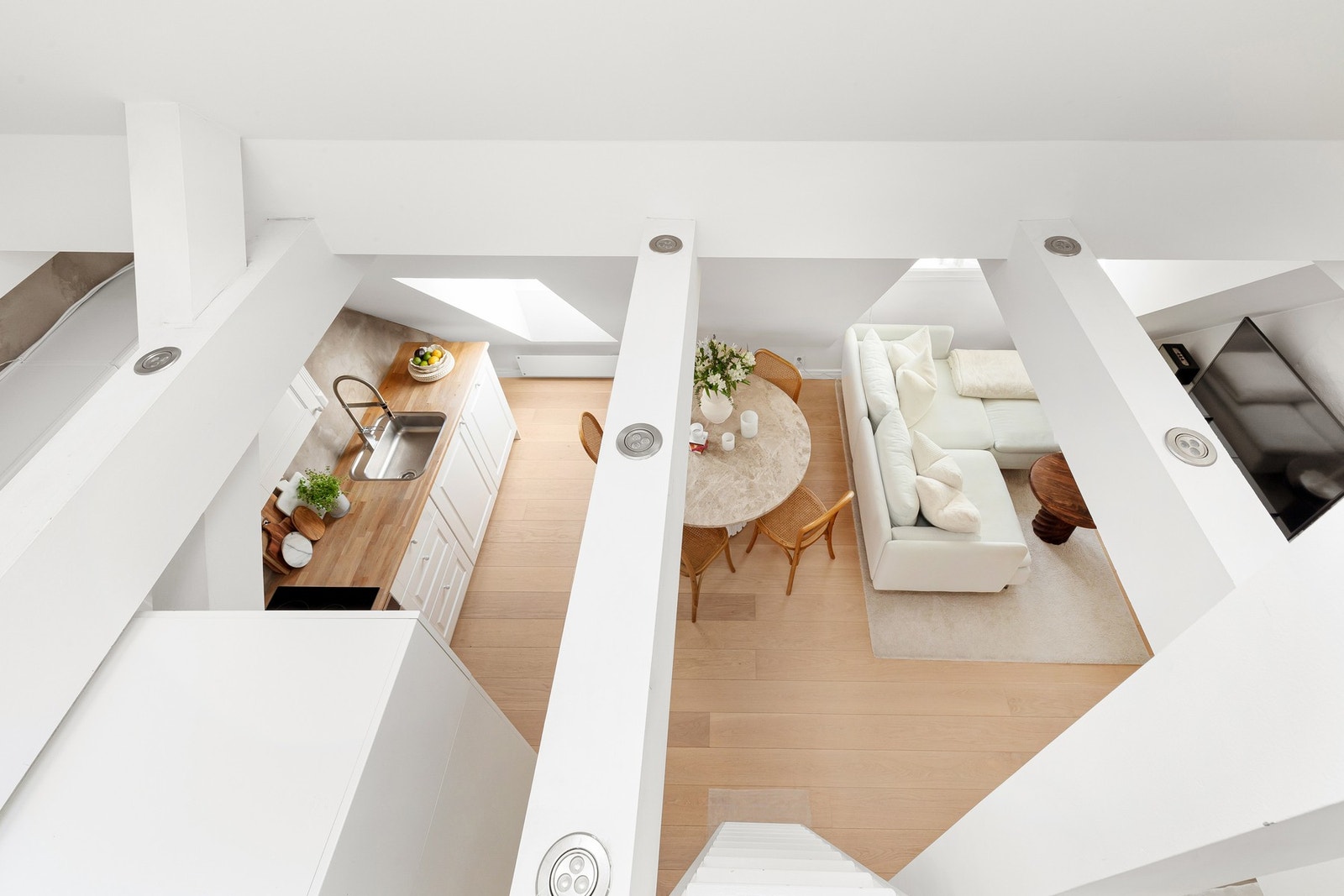 Sjenerøs takhøyde (mønehøyde på 4,55 m), malte bjelker, downlights og uplights gir leiligheten et unikt preg. Galleribilde