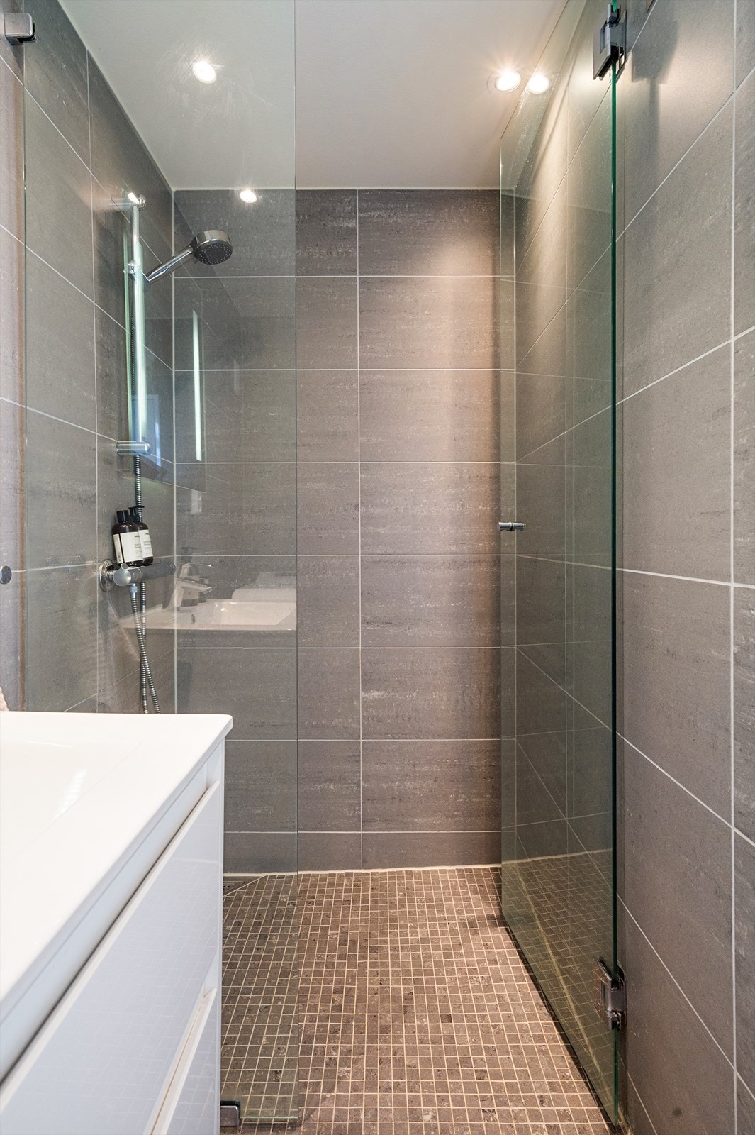 Badet er utstyrt med heldekkende servant på underskap, speil med belysning, vegghengt toalett og dusj med herdet glassvegger. Opplegg for vaskemaskin er også på plass. Galleribilde