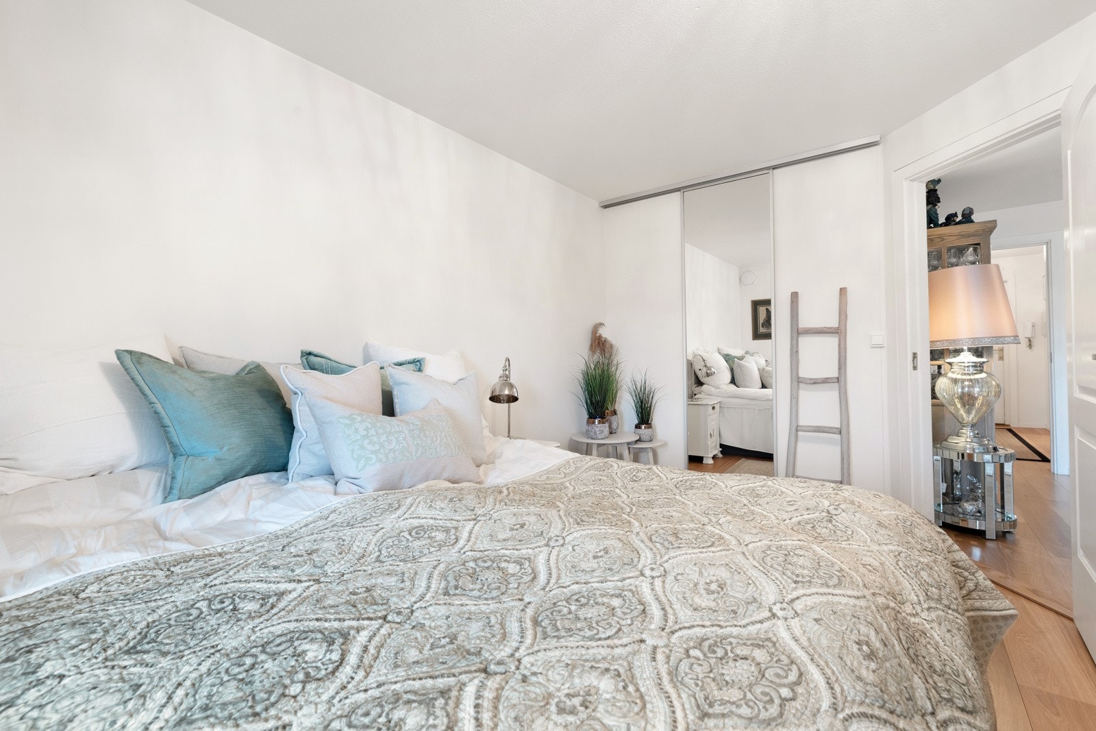 Soverommet er holdt i en stilren kombinasjon med hvitmalte vegger mot gyllent parkettgulv. Galleribilde