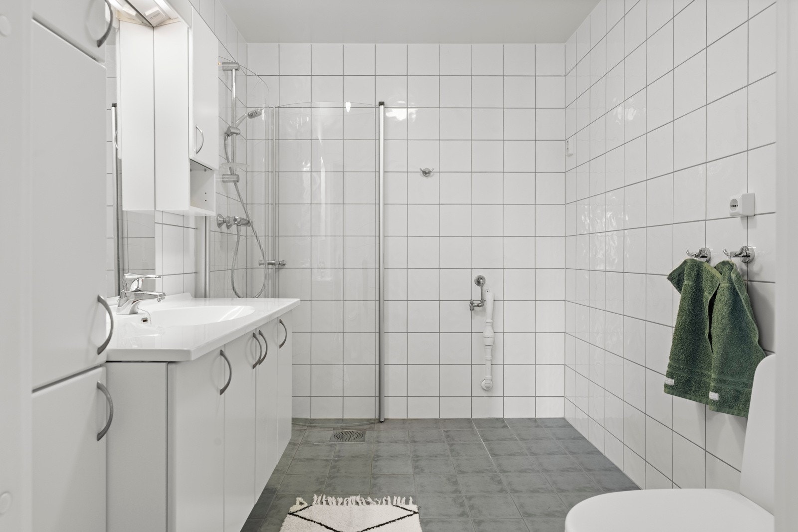 Badet er helfliset og innredet med gulvvarme, dusjhjørne, toalett og opplegg for vaskemaskin. Galleribilde