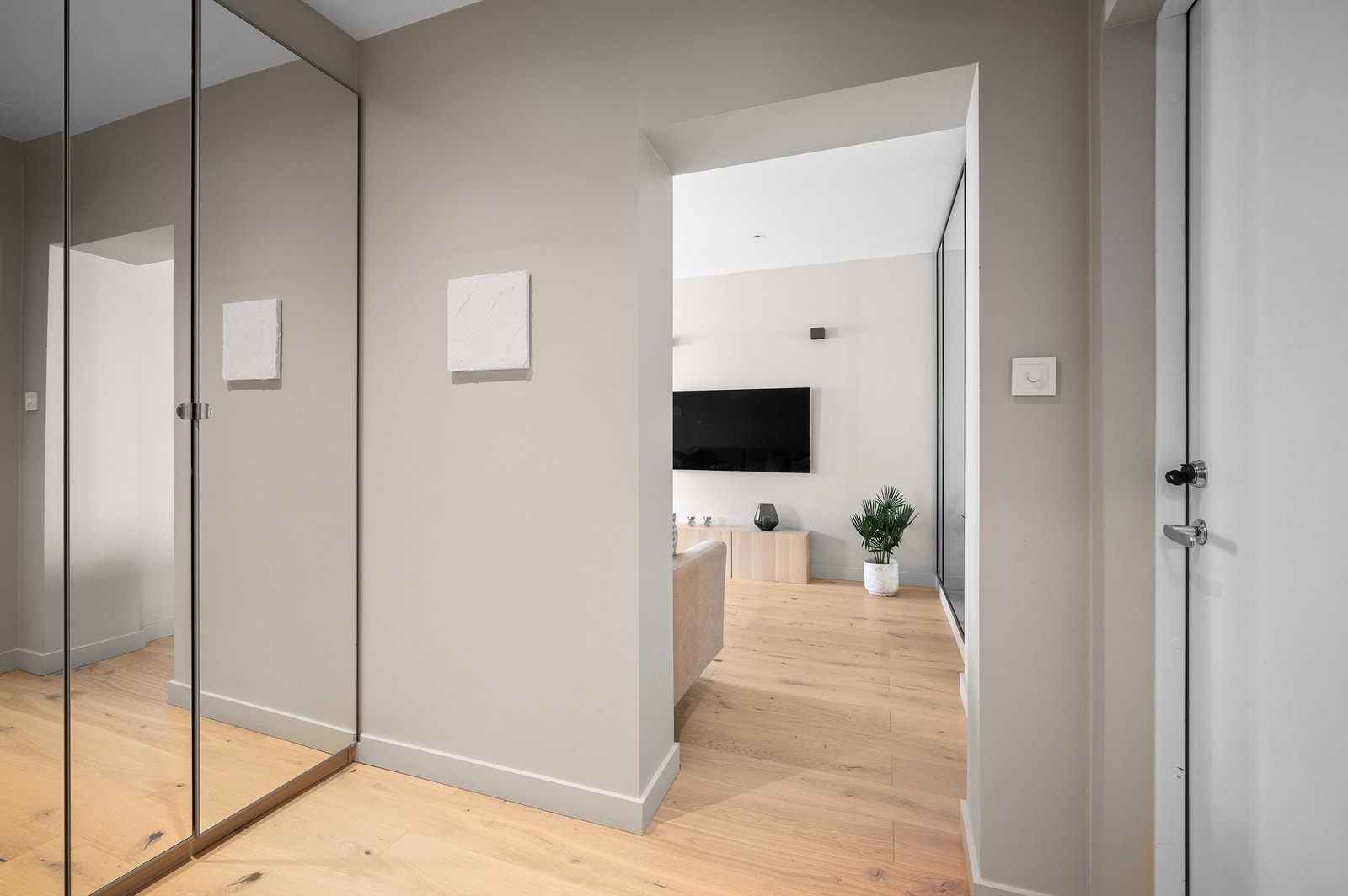 Entréen er pen og innbydende, som er med på å gi et godt førsteinntrykk av leiligheten. Det er montert callinganlegg ved inngangsdøren, og yttertøyet ryddes enkelt bort i garderobeskap med speilfronter. Galleribilde