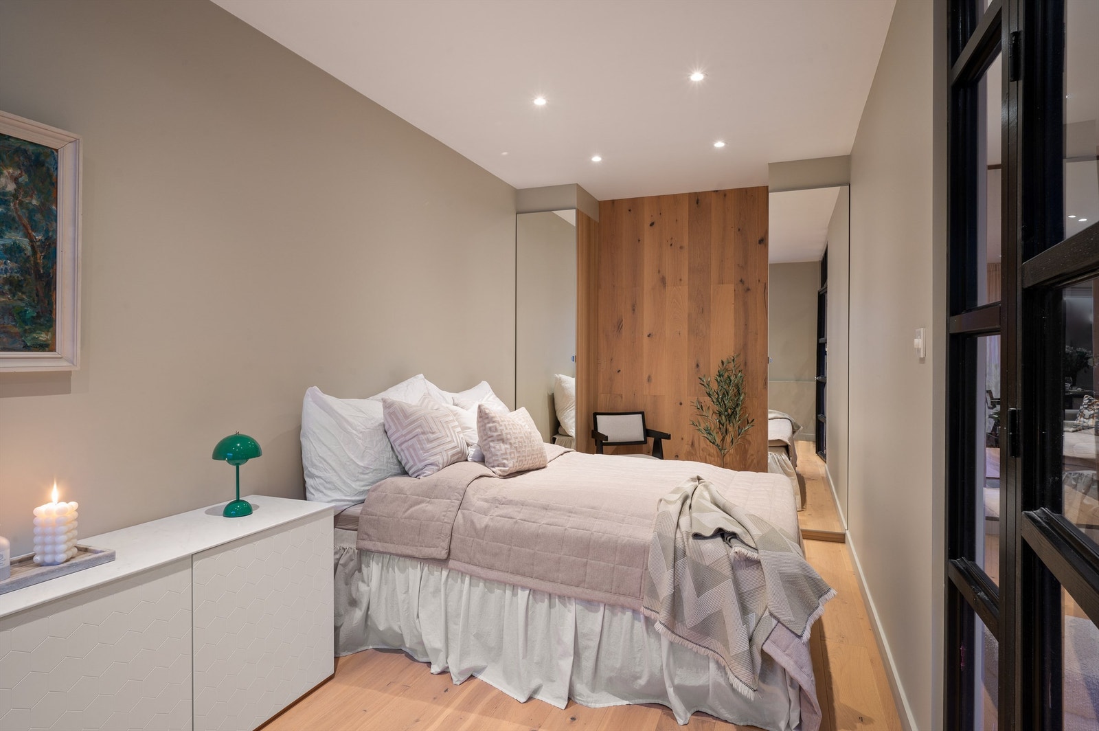 Via en stilfull glassvegg med sorte rammer er det adkomst fra stuen til et langstrakt og pent soverom. Galleribilde