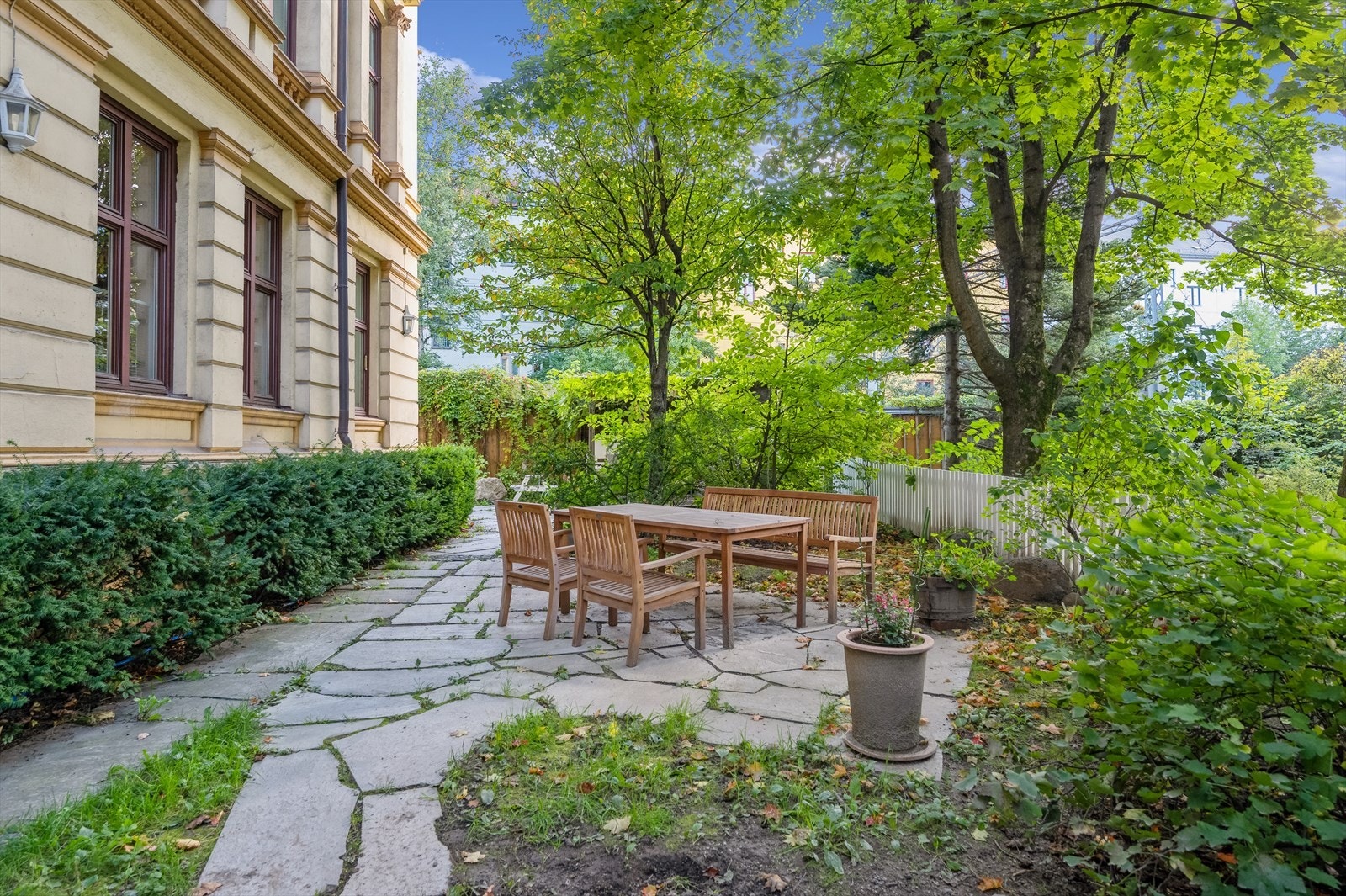 Sjarmerende og grønt felles uteområde med sittegruppe, ideelt for både avslapning og sosiale sammenkomster. Omgitt av frodig beplantning som gir en skjermet og hyggelig uteplass. Galleribilde