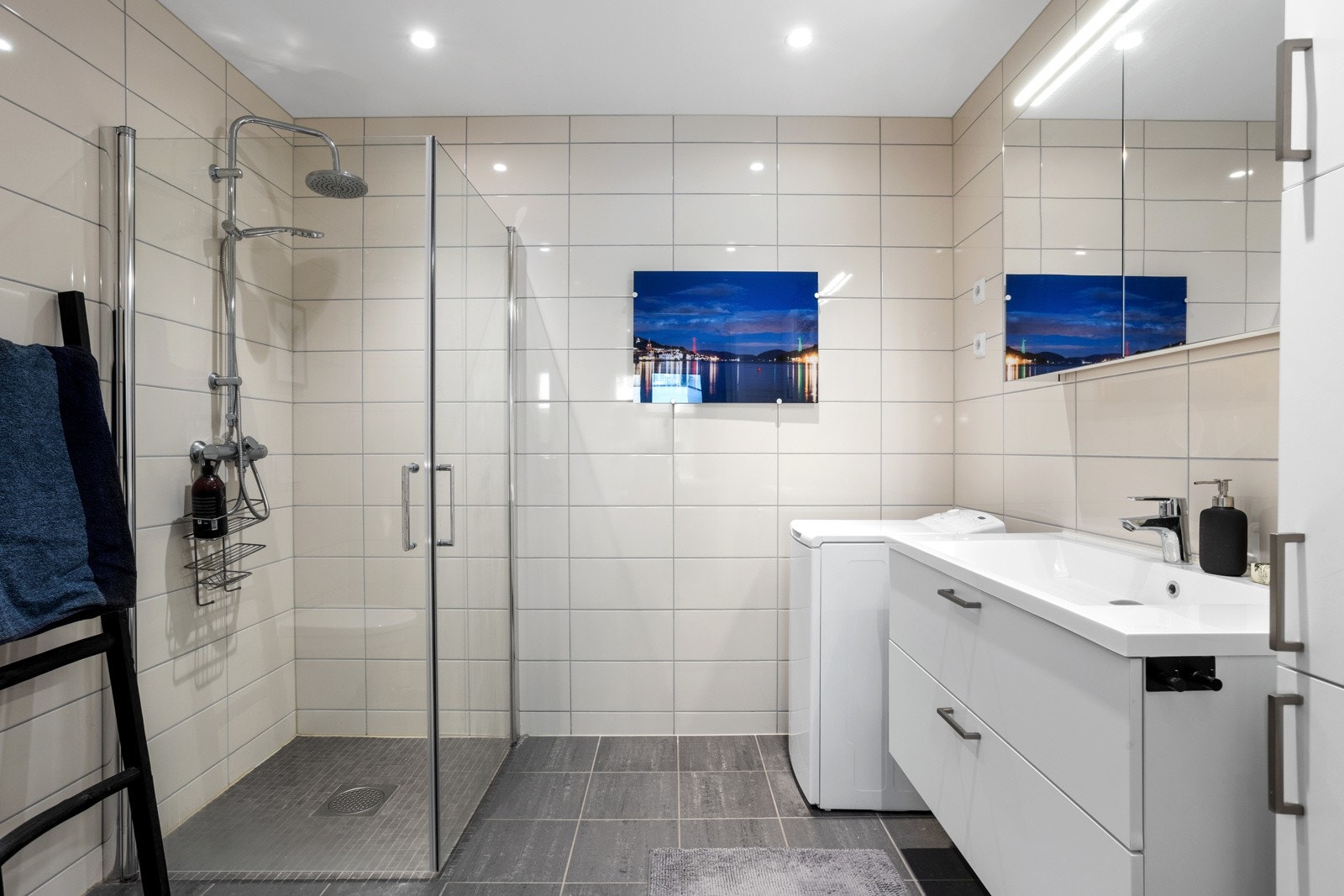 Pent flislagt baderom med varmekabler. Baderomsinnredningen besår av dusjhjørne med glassdører, vegghengt toalett, servantinnredning og det er montert opplegg for vaskemaskin Galleribilde