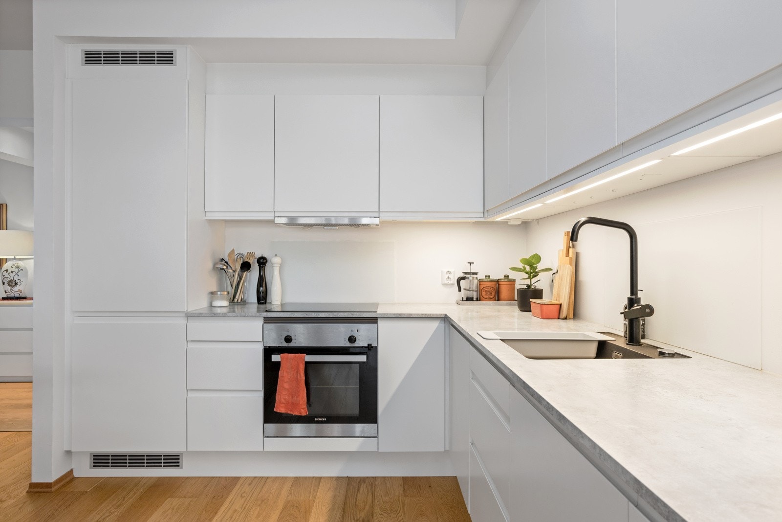 Kjøkkeninnredningen har skjulte håndtak og integrert stekeovn, platetopp, oppvaskmaskin og kjøleskap med fryser Galleribilde