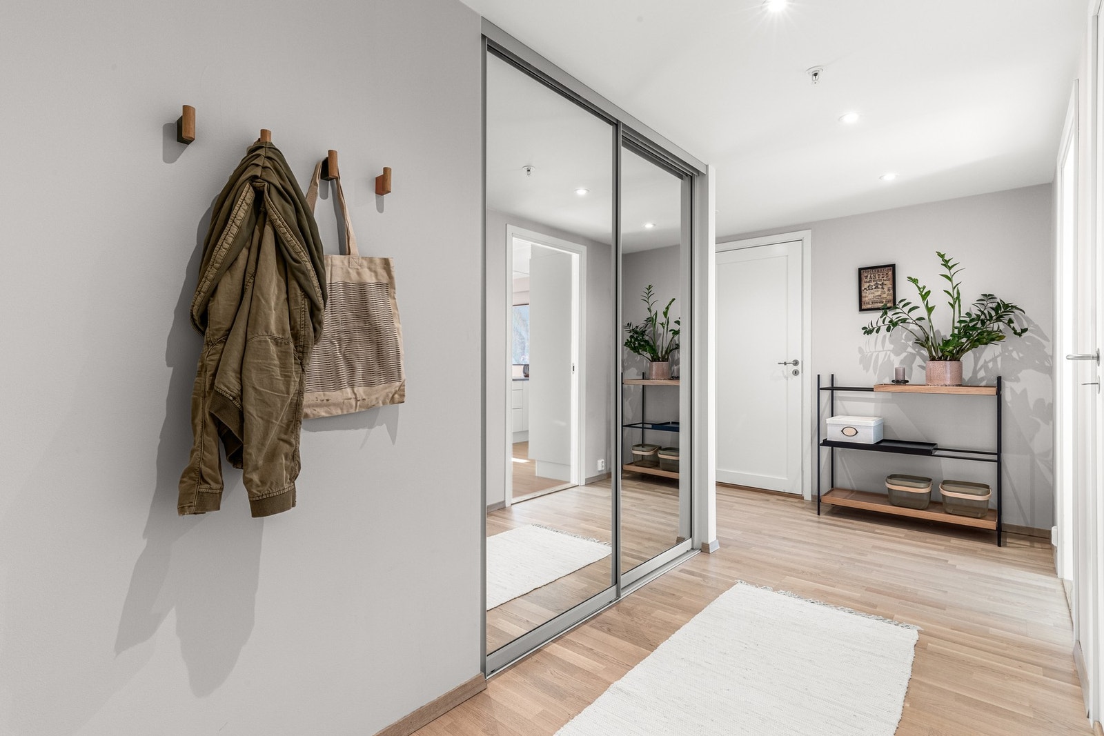 Romslig og fin entré med downlights i himling, lyst 3-stavs parkettgulv med innfelt skyvedørsgarderobe Galleribilde