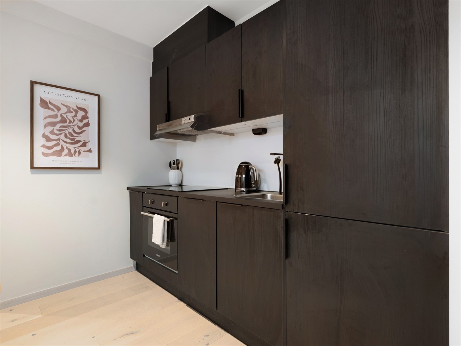 Stilrent fullverdig kjøkken med lik innredning som i leilighetens hoveddel, og laminat benkeplate. Kjøkkeninnredningen ble oppført ny i 2022. Galleribilde