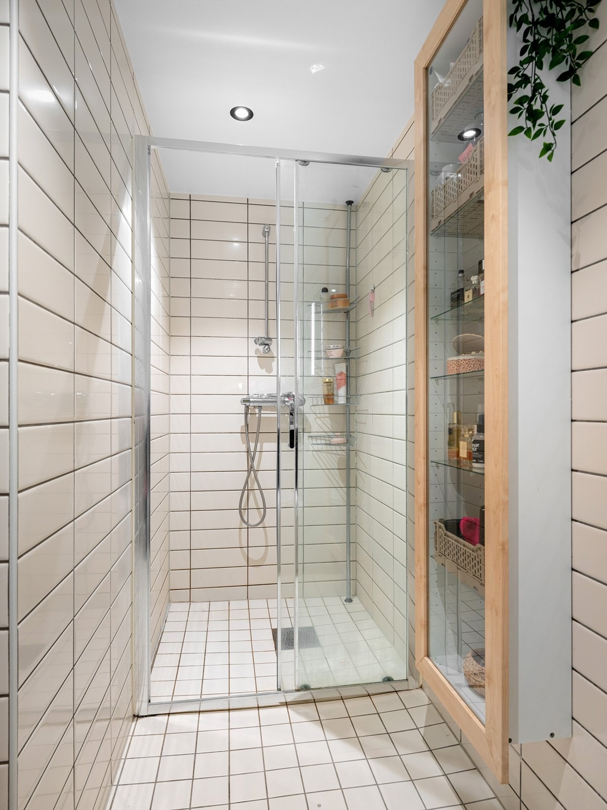 Praktisk og romslig dusjhørne med oppbevaring for smånips i vegghengt glasskap t.h. Galleribilde