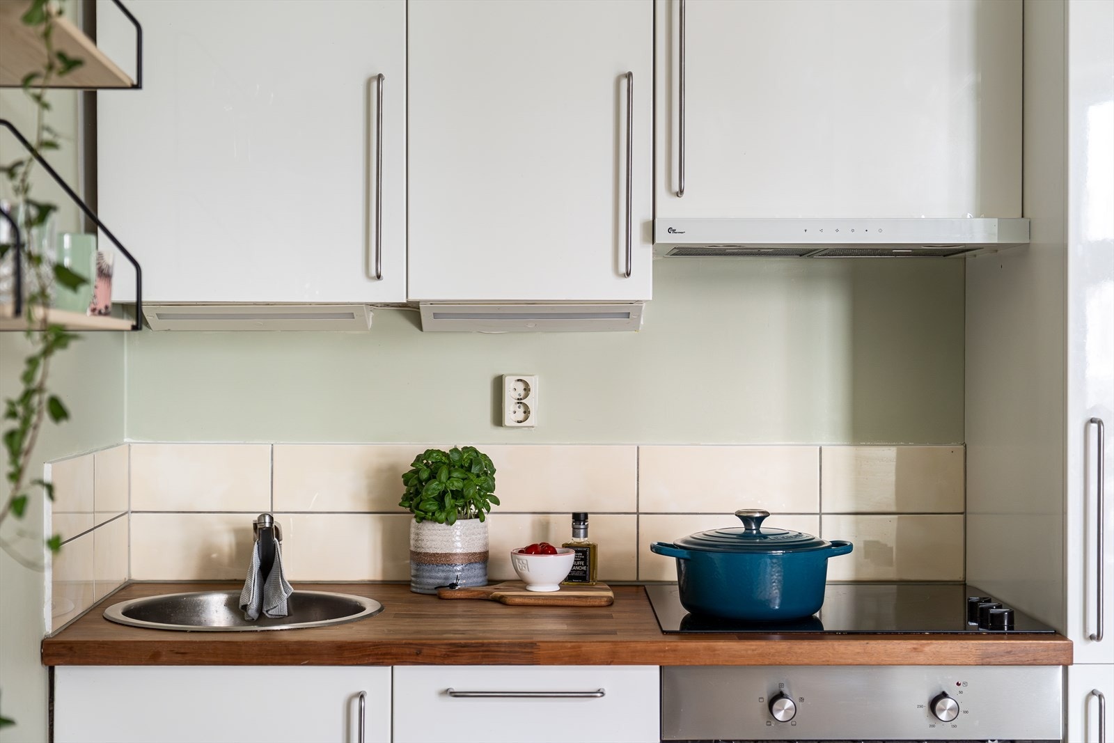 Kjøkkeninnredningen har hvite, høyglans fronter og finert benkeplate med nedfelt kum i rustfritt stål. Galleribilde