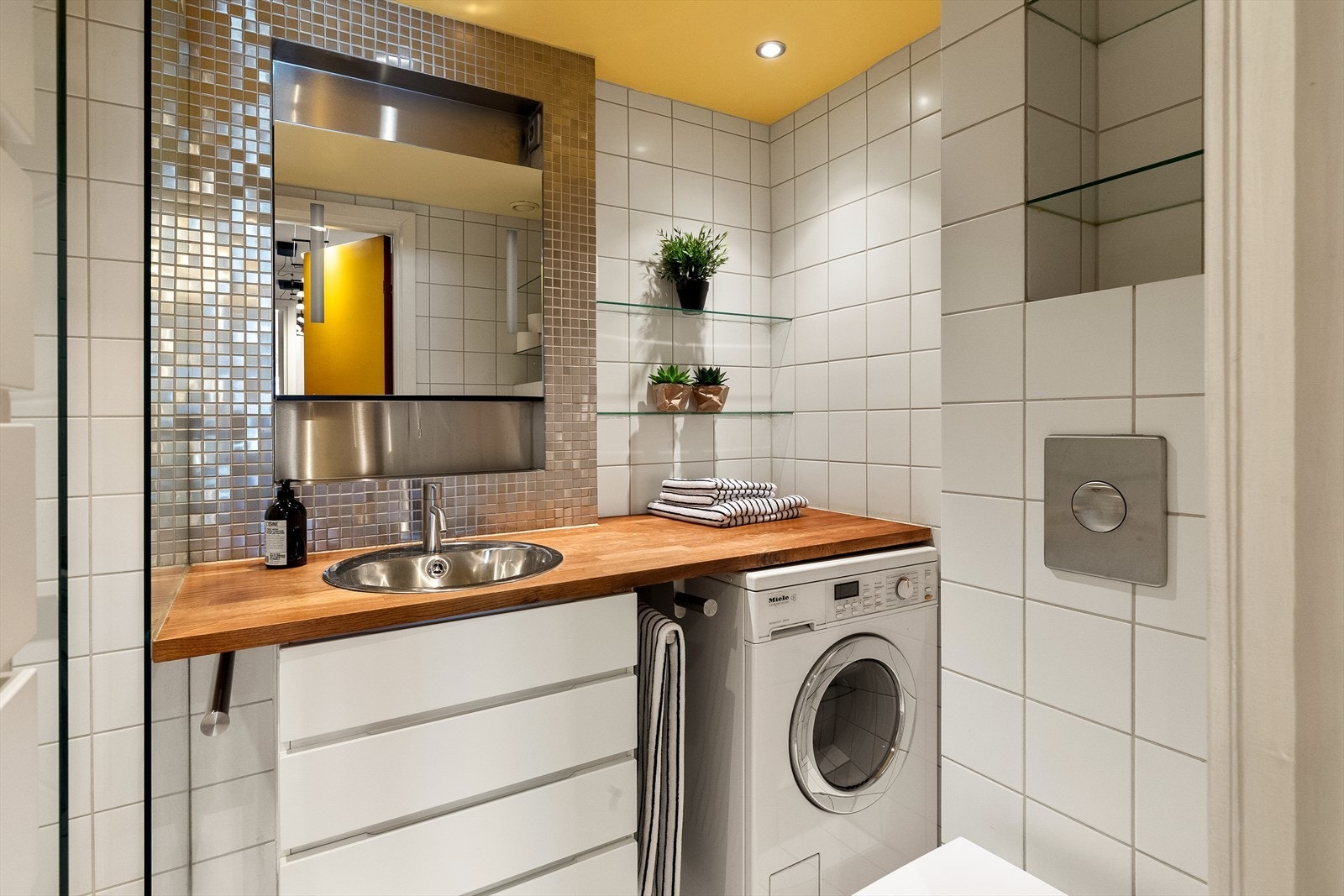 Romslig baderom med fliser på vegg og gulv. Taket har downlights, varmekabler på gulv og opplegg for vaskemaskin. Galleribilde