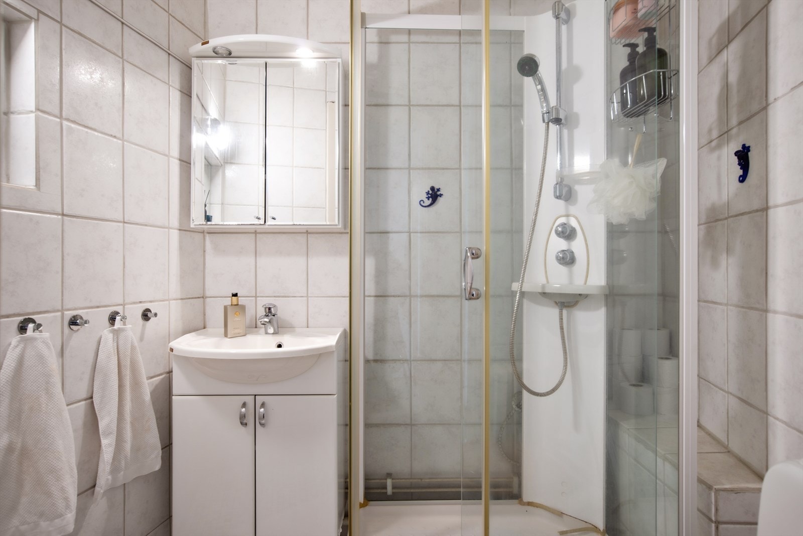 Flislagt bad med WC, dusjkabinett og servant med ettgreps blandebatteri i innredning Galleribilde