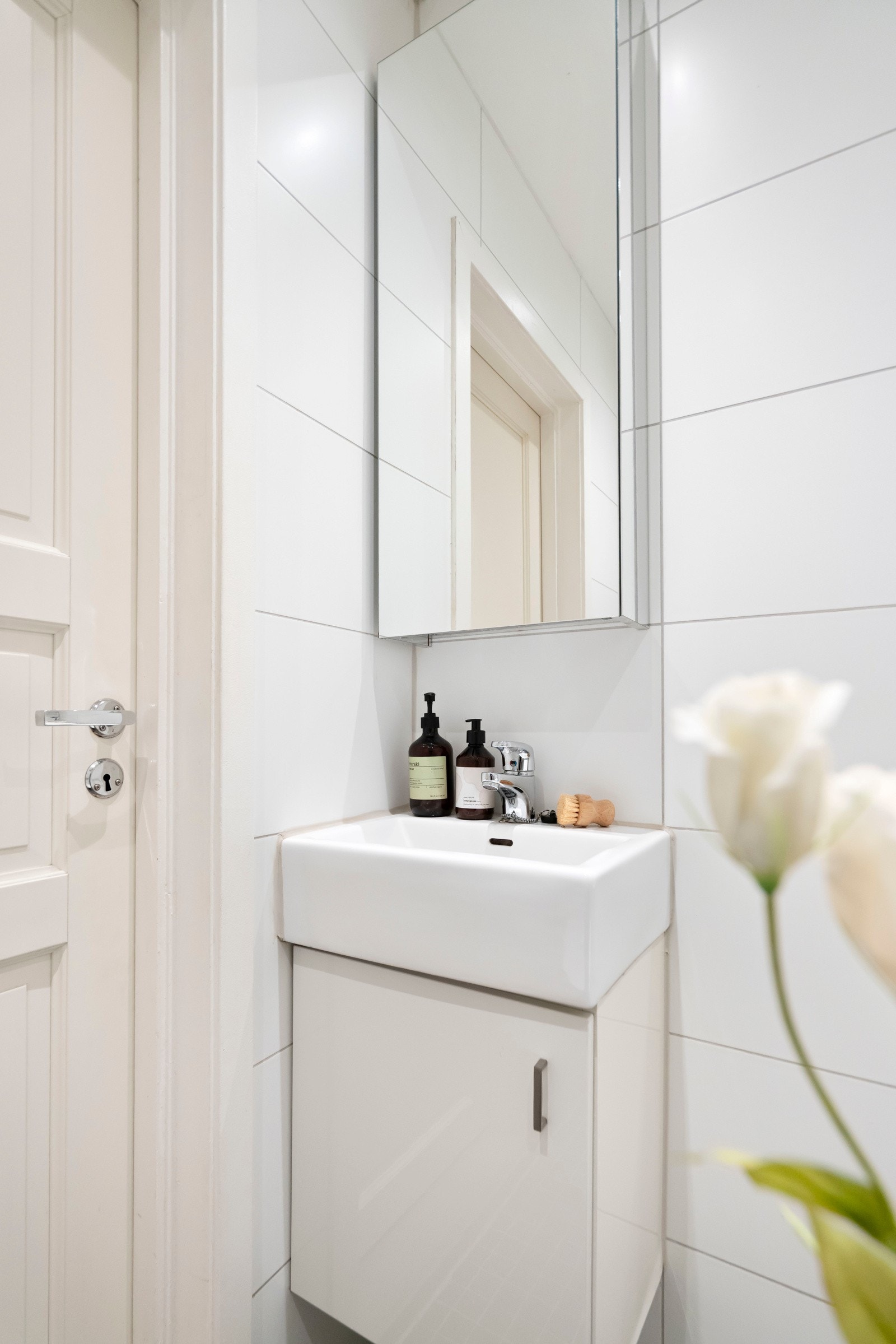 Lys innredning med servant med ett greps blandebatteri og underskap, veggmontert toalett og dusjplass med inn-utadslående dusjvegger. Galleribilde