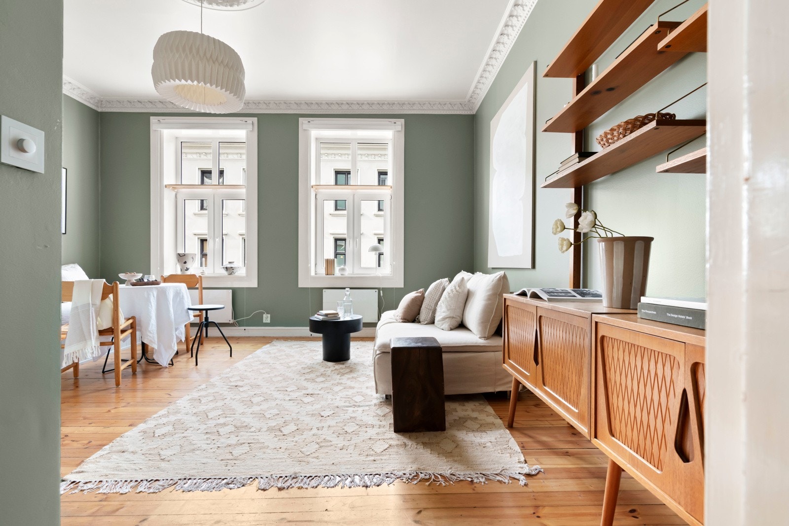 Hyggelig stue i en sosial, åpen løsning mot kjøkkenet, med flotte klassiske detaljer som stukkatur og rosett. Galleribilde