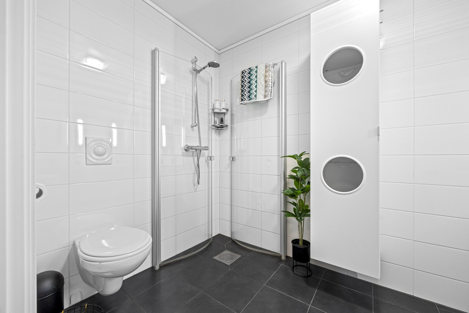 Bad/vaskerom med vegghengt toalett, dusj, servant med vask og opplegg til vaskemaskin Galleribilde