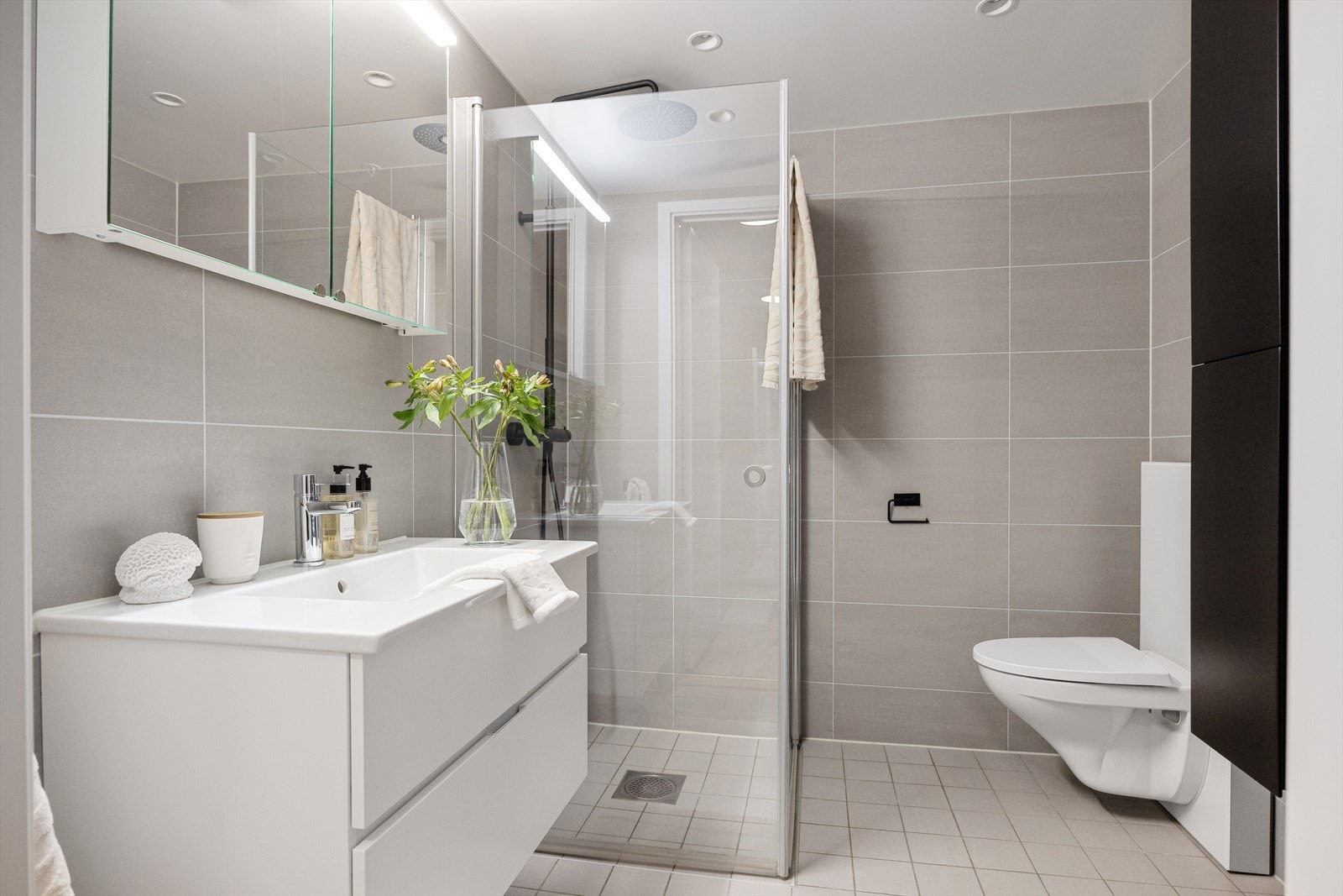 Badet er utstyrt med servant, skap, speil, belysning og veggmontert toalett. Galleribilde
