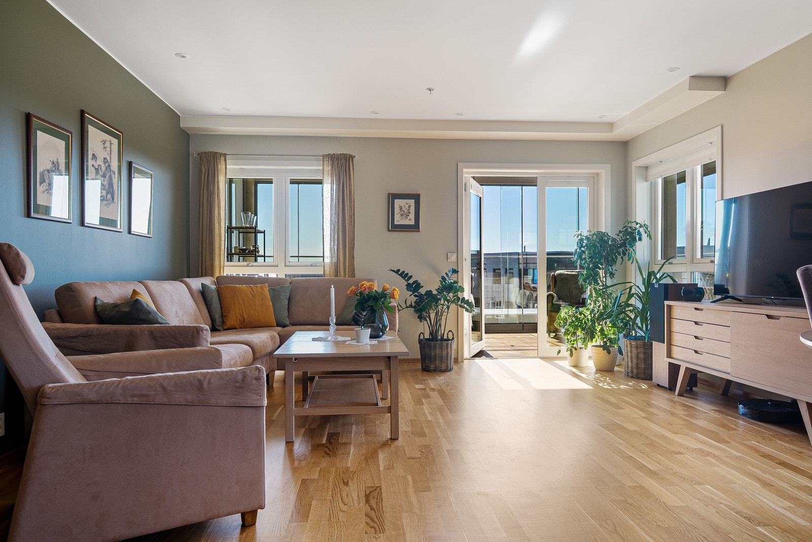 En stor og lys stue som leder ut til den innglassede balkongen. Galleribilde