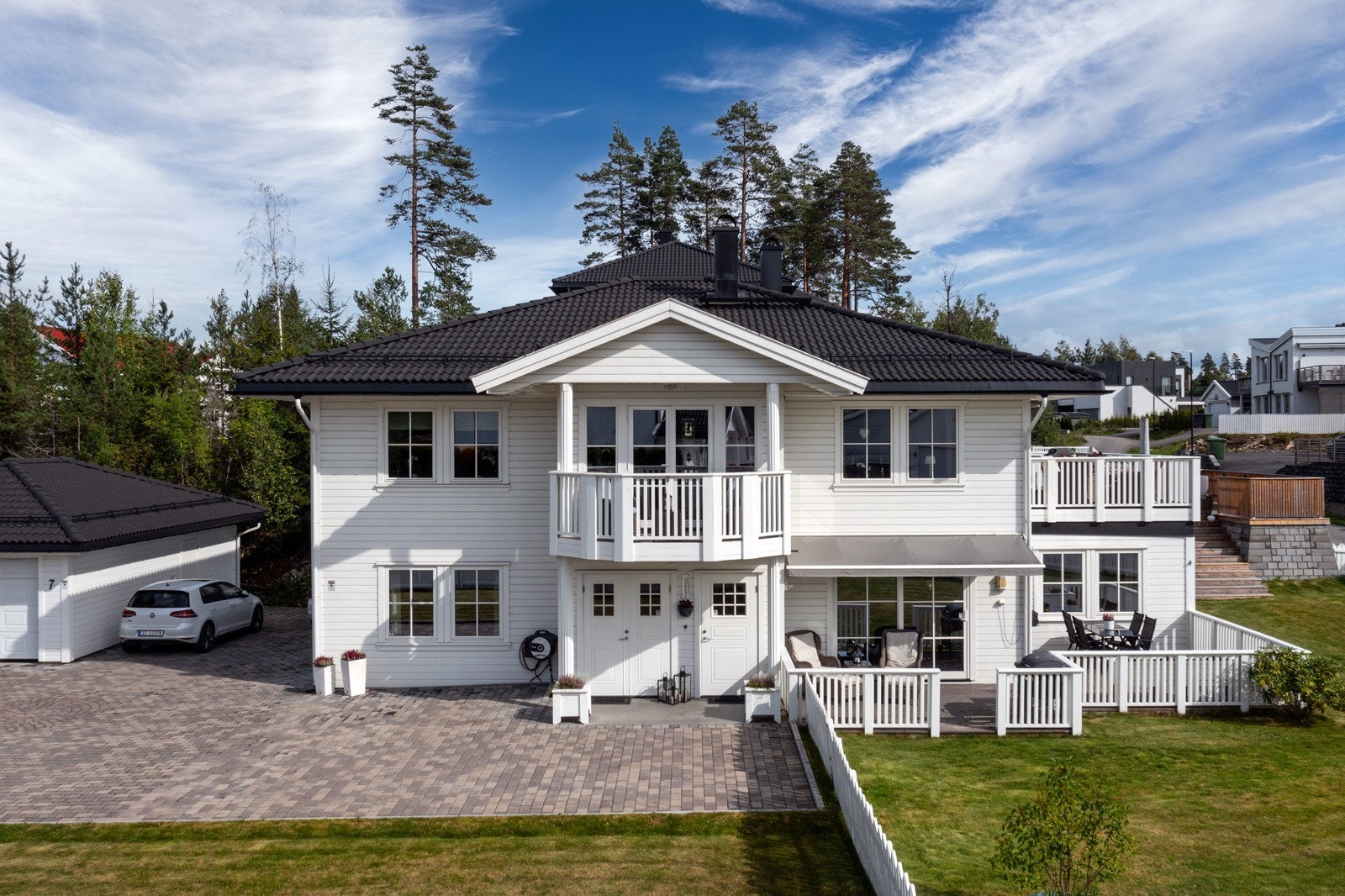 Stor steinlagt innkjørsel og gårdsplass. Flott støttemur i bakkant mot terrassen. Galleribilde