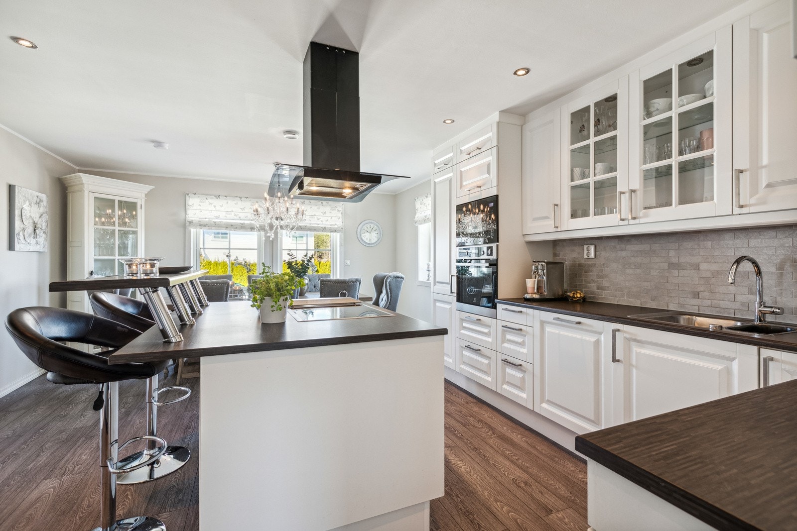 Kjøkkenøy med integrert induksjonsplatetopp, fritthengende stålventilator og ekstra sitteplasser i barløsning. Galleribilde