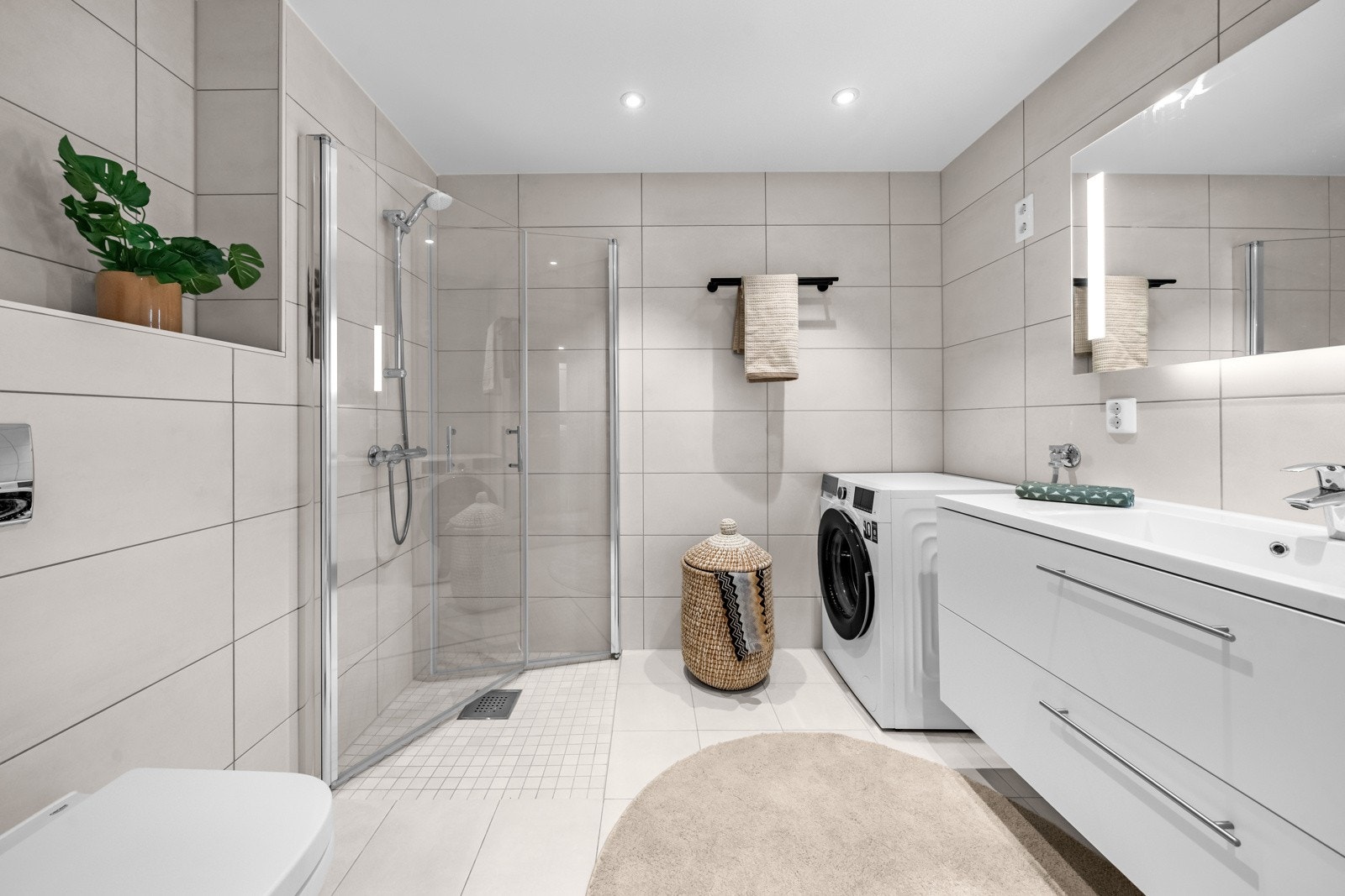 Delikat baderom med gulvvarme og opplegg for vaskemaskin og tørketrommel Galleribilde