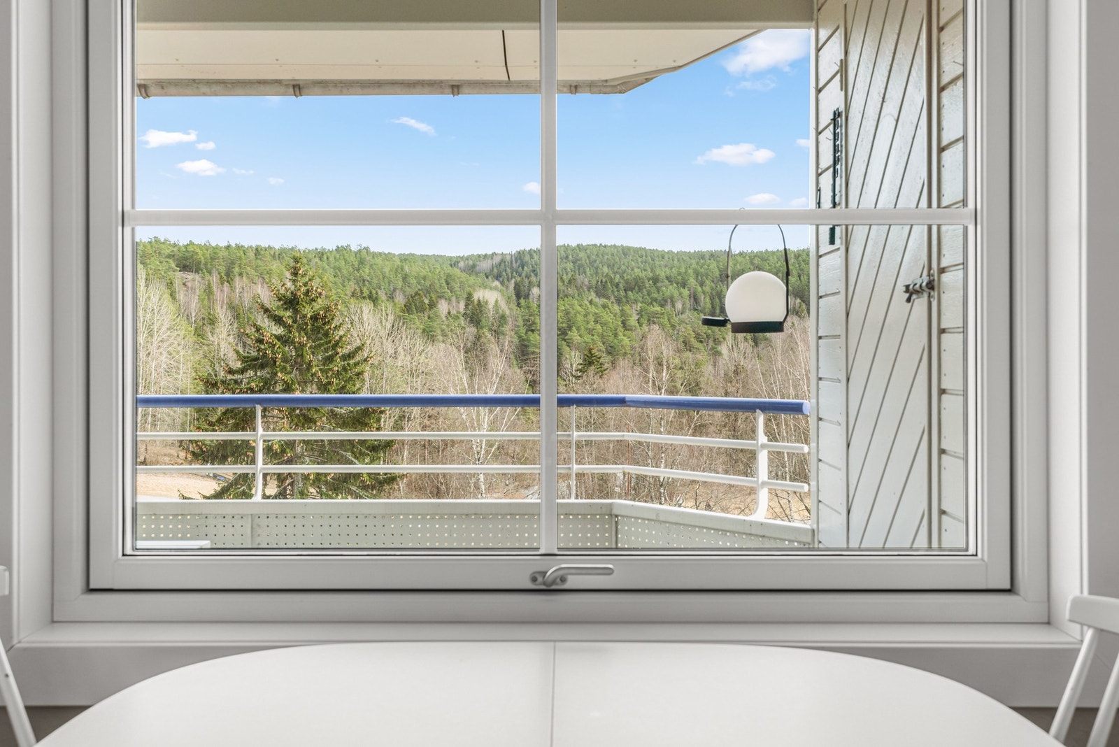 Et stor vindu på kjøkkenet ved spiseplass sørger for godt med lysinnslipp Galleribilde