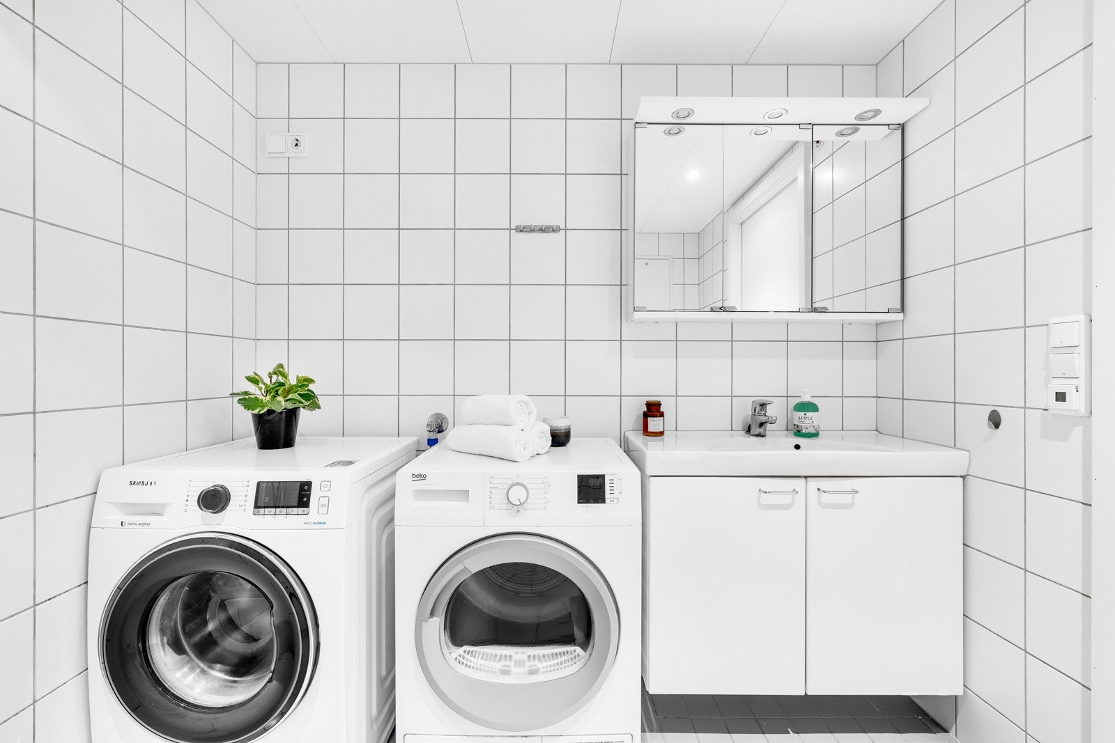 Baderomsinnredningen har hvite, glatte fronter og består av en heldekkende servant på en skapseksjon og et bredt speilskap med belysning. Galleribilde