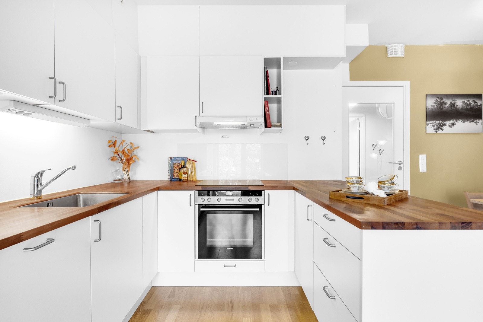 Kjøkkenet fra Norema har et stilfullt og moderne design med gode benkeflater. Innredningen har hvite, glatte fronter og gyllen heltrebenkeplate med underlimt kum i stål. Galleribilde