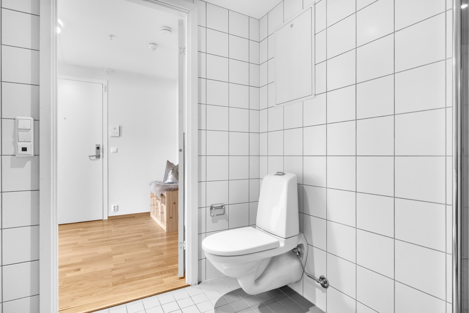 Videre er badet utstyrt med toalett, opplegg for vaskemaskin og et dusjhjørne med innfellbare, plassbesparende glassdører. Galleribilde