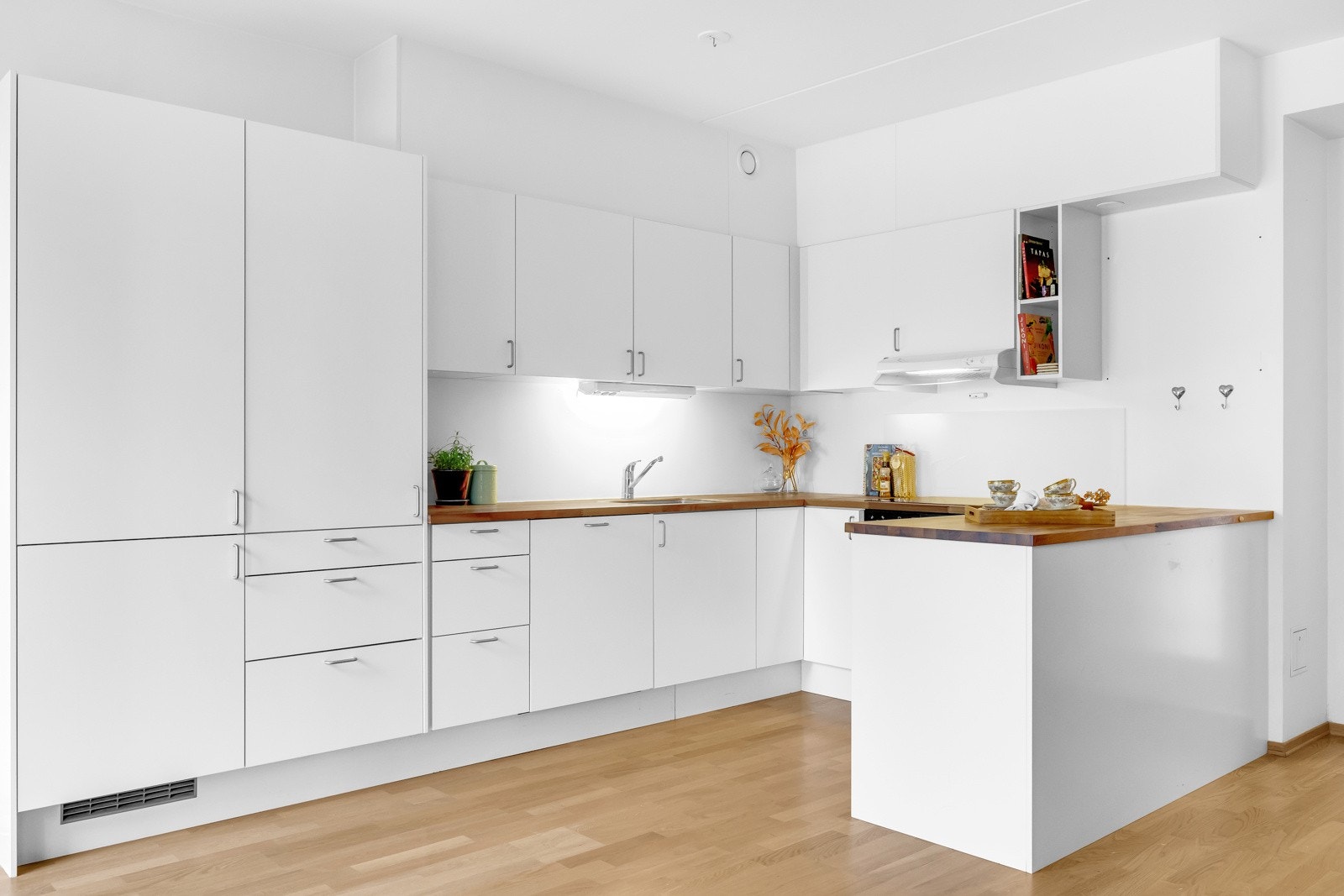 Kjøkkenet er utstyrt med integrerte hvitevarer som oppvaskmaskin, kjøleskap, stekeovn og koketopp, samt ventilator, benkestikk og god arbeidsbelysning. Galleribilde