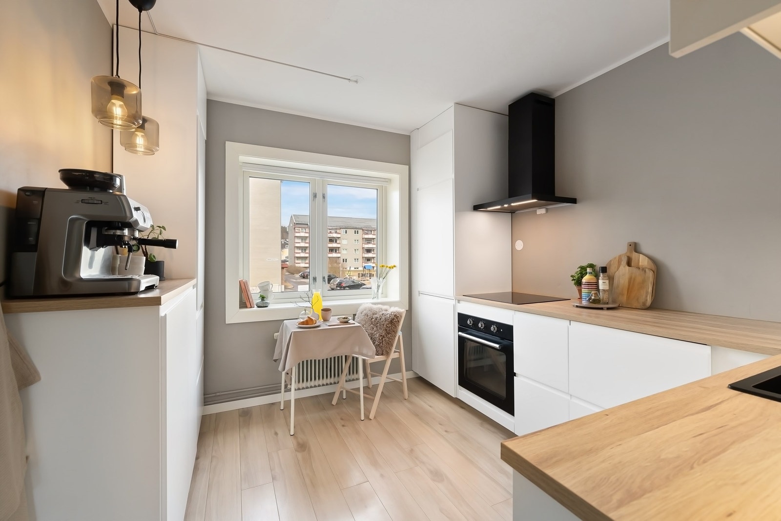 Kjøkkeninnredning med slette fronter. Benkeplate av laminat. Benkeskapsbelysning og stikkontakt over benkeplate. Integrerte hvitevarer. Galleribilde