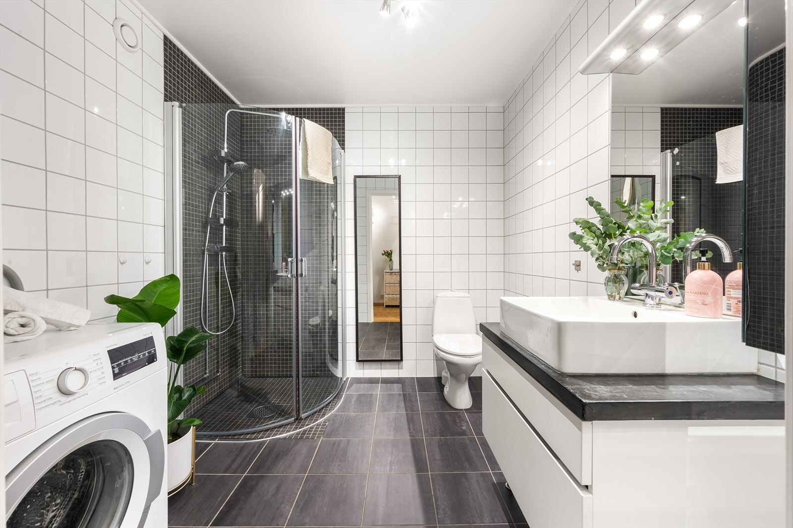 Tidløst og romslig bad med flislagte overflater, elektrisk gulvvarme og mekanisk avtrekk. Det er opplegg for vaskemaskin. Galleribilde