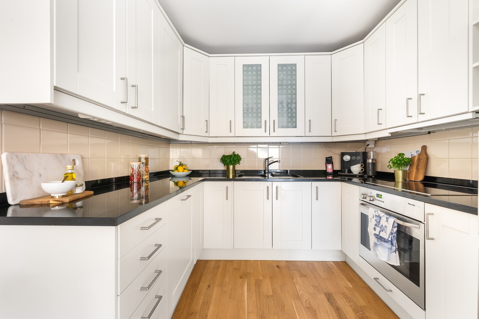 Lys innredning med glatte fronter og benkeplate av stein med nedfelt vask. Selger opplyser at det ble montert nye armatur på kjøkken i 2024. Galleribilde