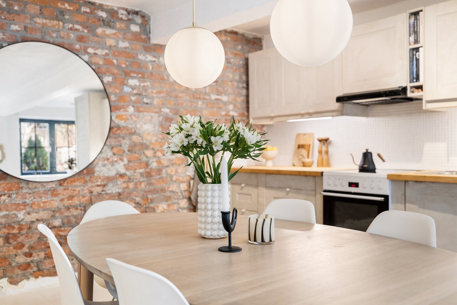 Kjøkkeninnredning med malte, profilerte fronter, mosaikkfliser på vegg og heltre benkeplate. Over kjøkkenbenken er det belysning. Galleribilde