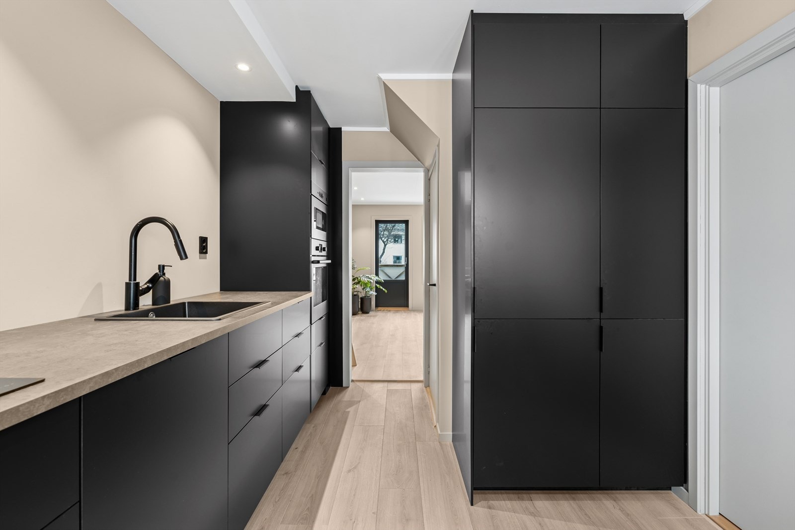 Kjøkkeninnredningen er fra 2024 med sorte slette fronter og benkeplate med nedfelt sort servant Galleribilde