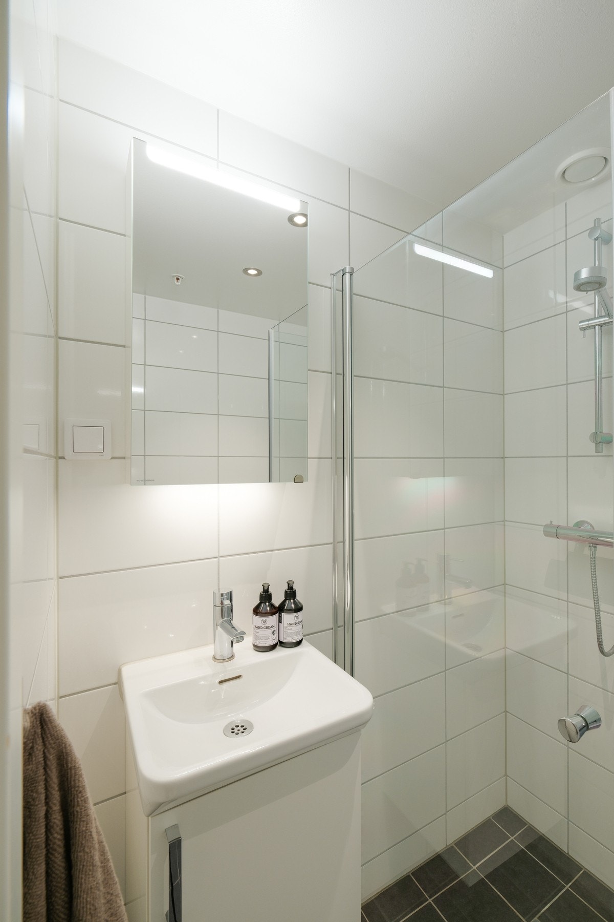 Badet har dusjhjørne, vegghengt toalett, servant og speil. Galleribilde