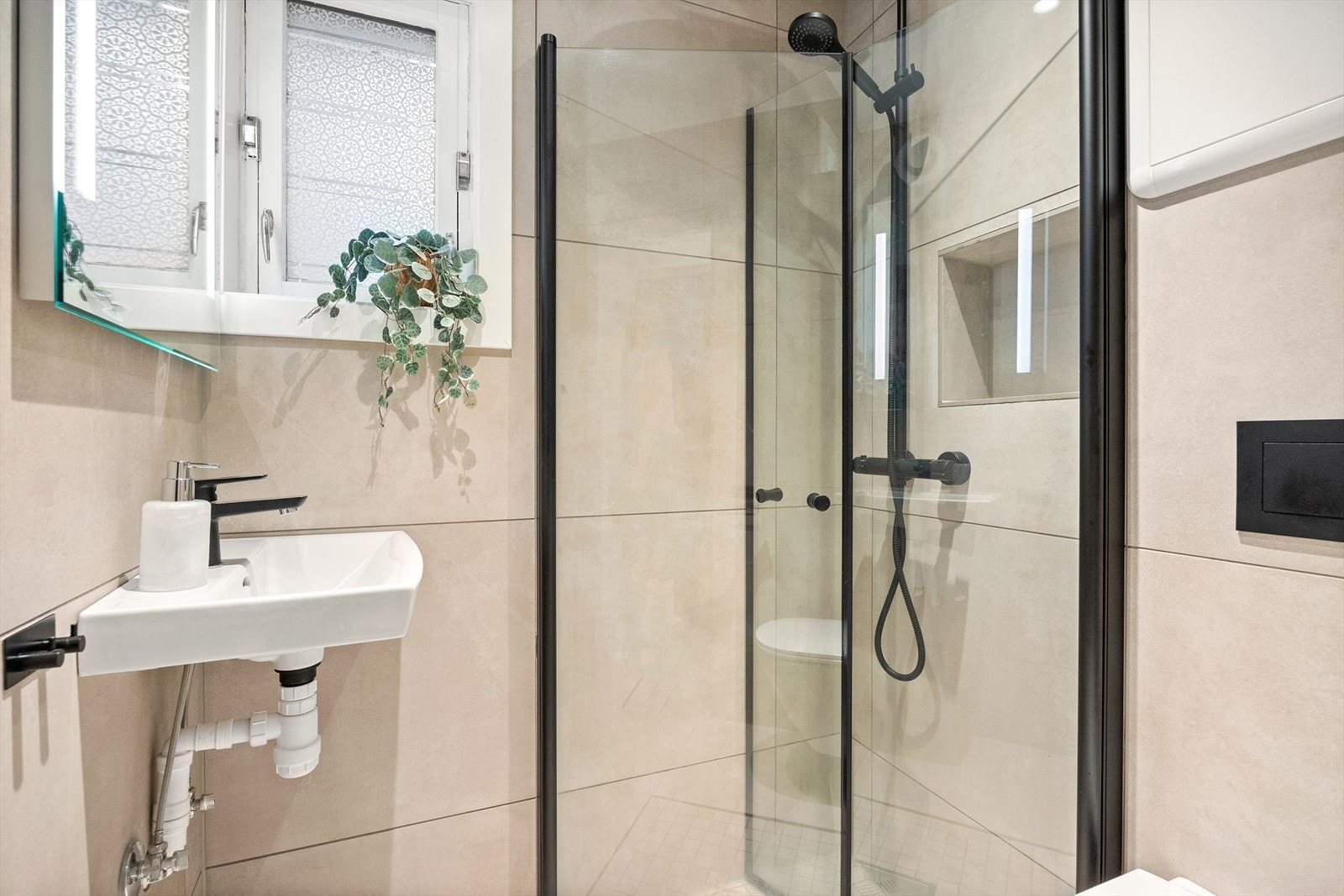 Badet et innredet med vegghengt toalett, vask, dusj og opplegg for vaskemaskin. Galleribilde