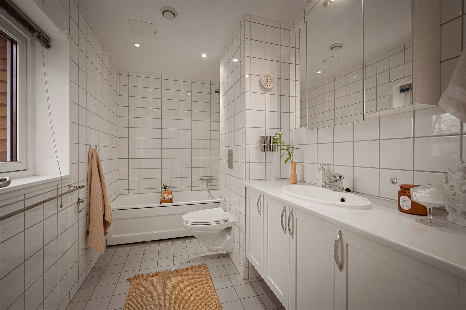 Innredningen består av toalett, servant med hvite profilerte fronter, speilskap med belysning og et frittstående badekar. Galleribilde