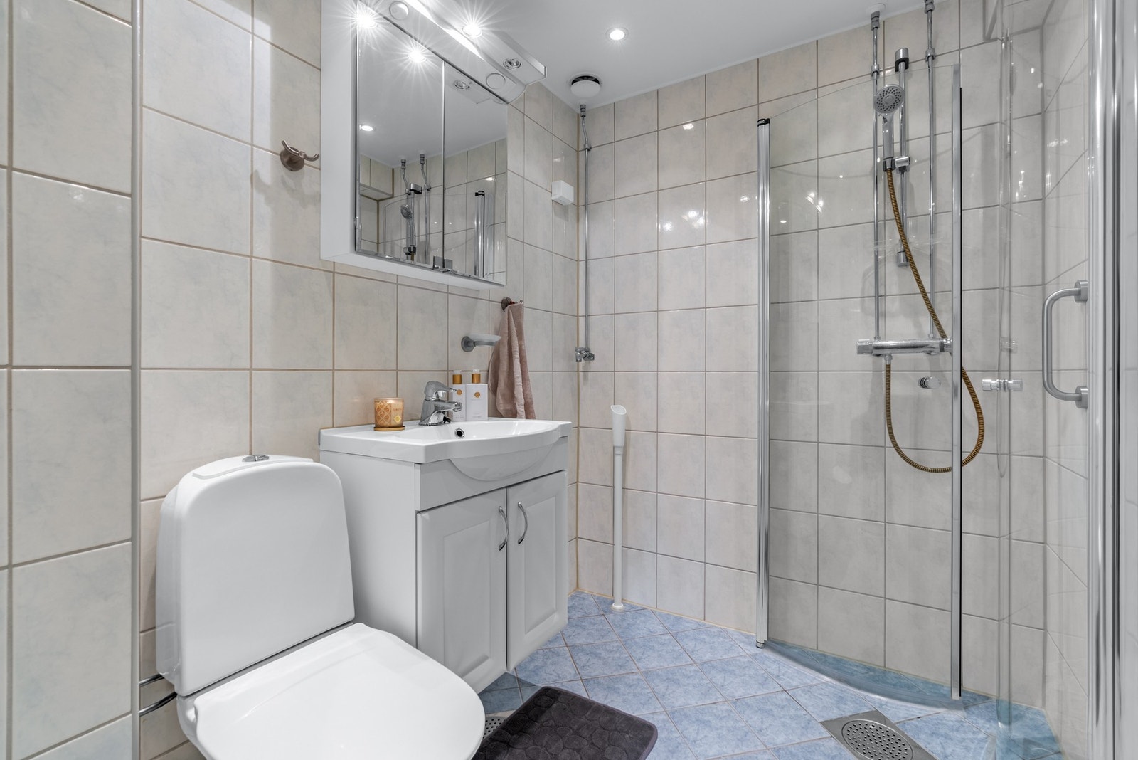 Badet er utstyrt med gulvmontert klosett, dusjhjørne med svingdører i glass, samt servantskap med profilerte folierte fronter med heldekkende servant. Det er opplegg for vaskemaskin. Galleribilde