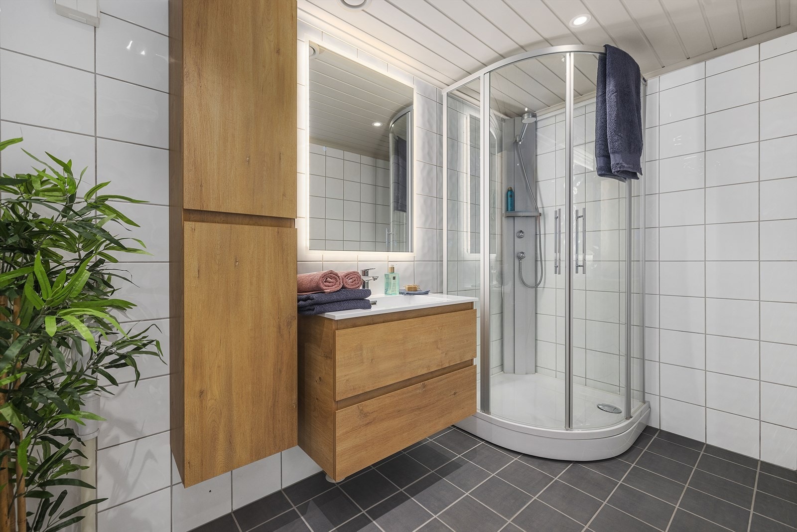 Baderommet er romslig, med pene, nøytrale fliser på vegger og gulv, med varmekabler Galleribilde