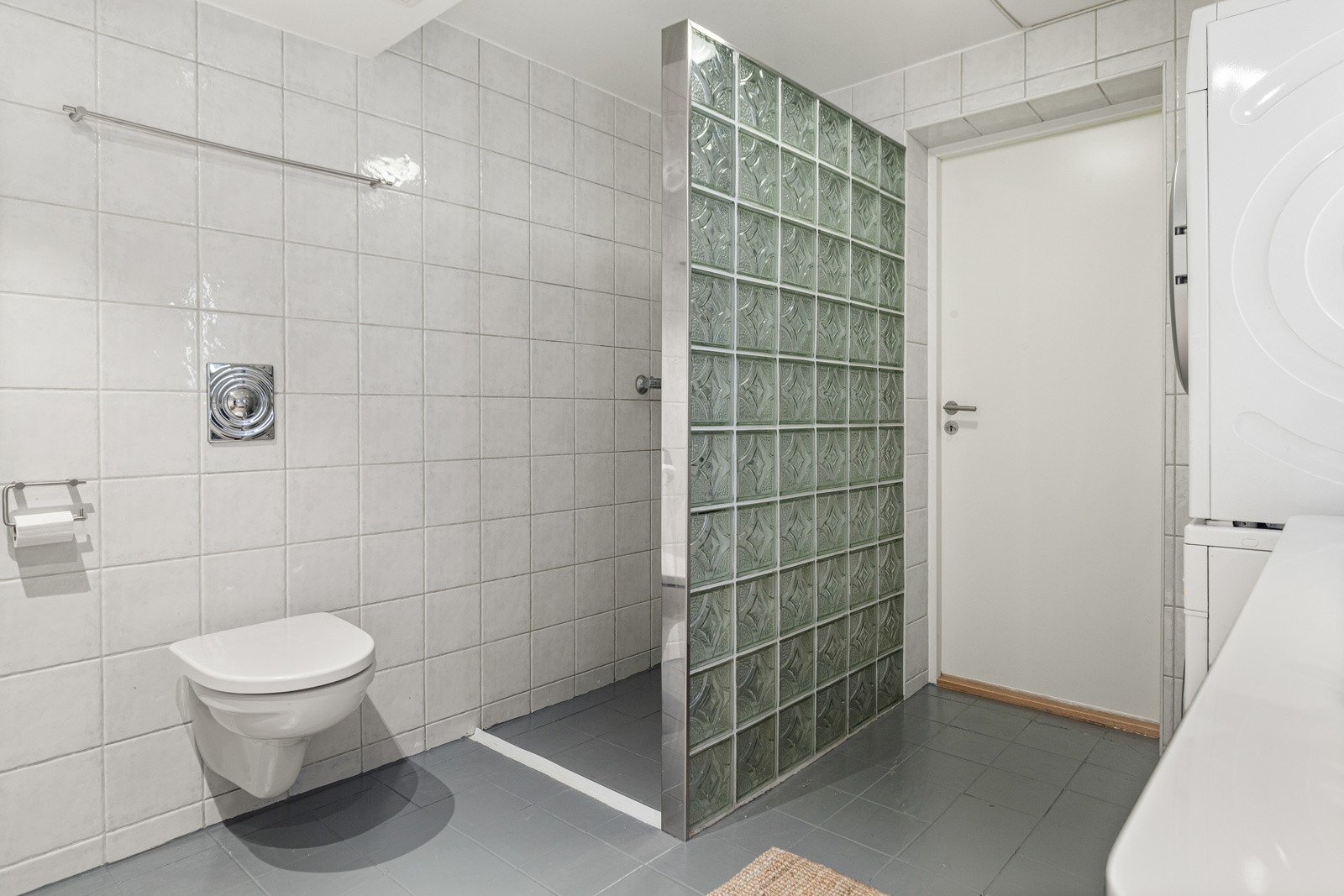 Badet er innredet med vegghengt toalett, servant med skuffer under og dusjnisje. Galleribilde