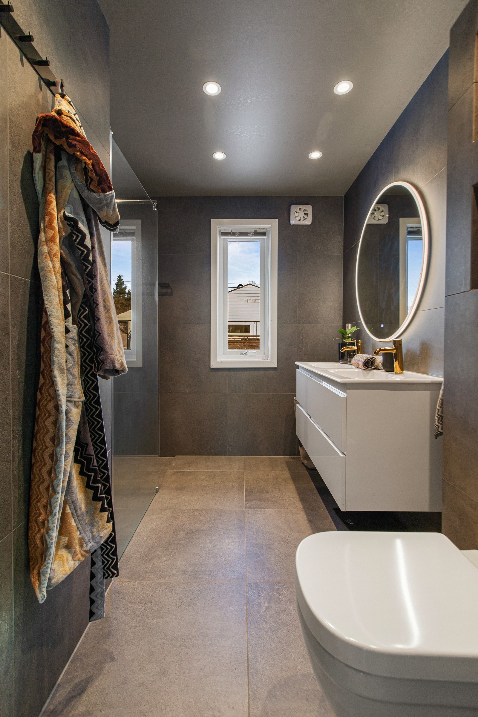 Badet er innredet med vegghengt toalett, servant med skuffer under og dusj med glassvegg og regnfallsdusj. Galleribilde