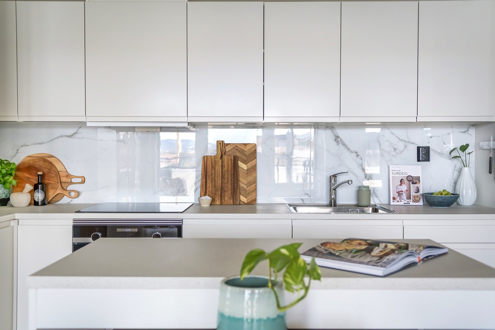 Lekker kjøkkeninnredning med hvite, glatte fronter og laminert benkeplate. Galleribilde