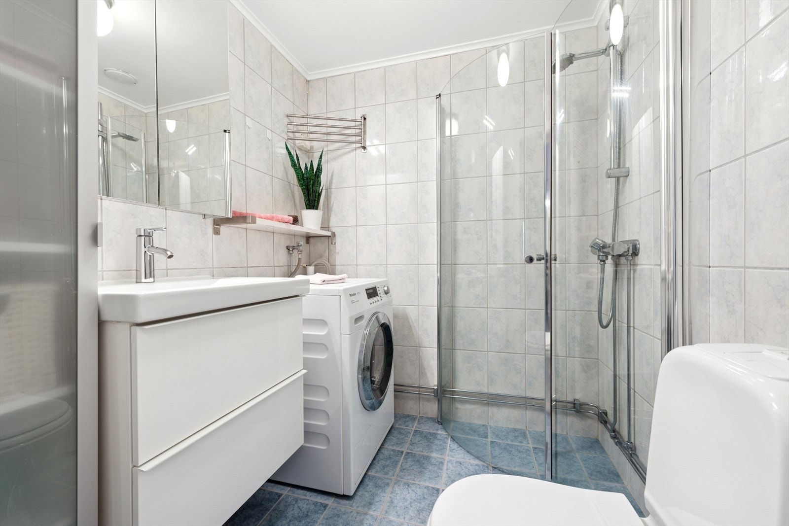 Flislagt bad, pusset opp i regi av borettslaget i 2004. Badet er utstyrt med dusjvegger fra 2013, nedfelt servant fra 2024, toalett og opplegg for vaskemaskin. Galleribilde