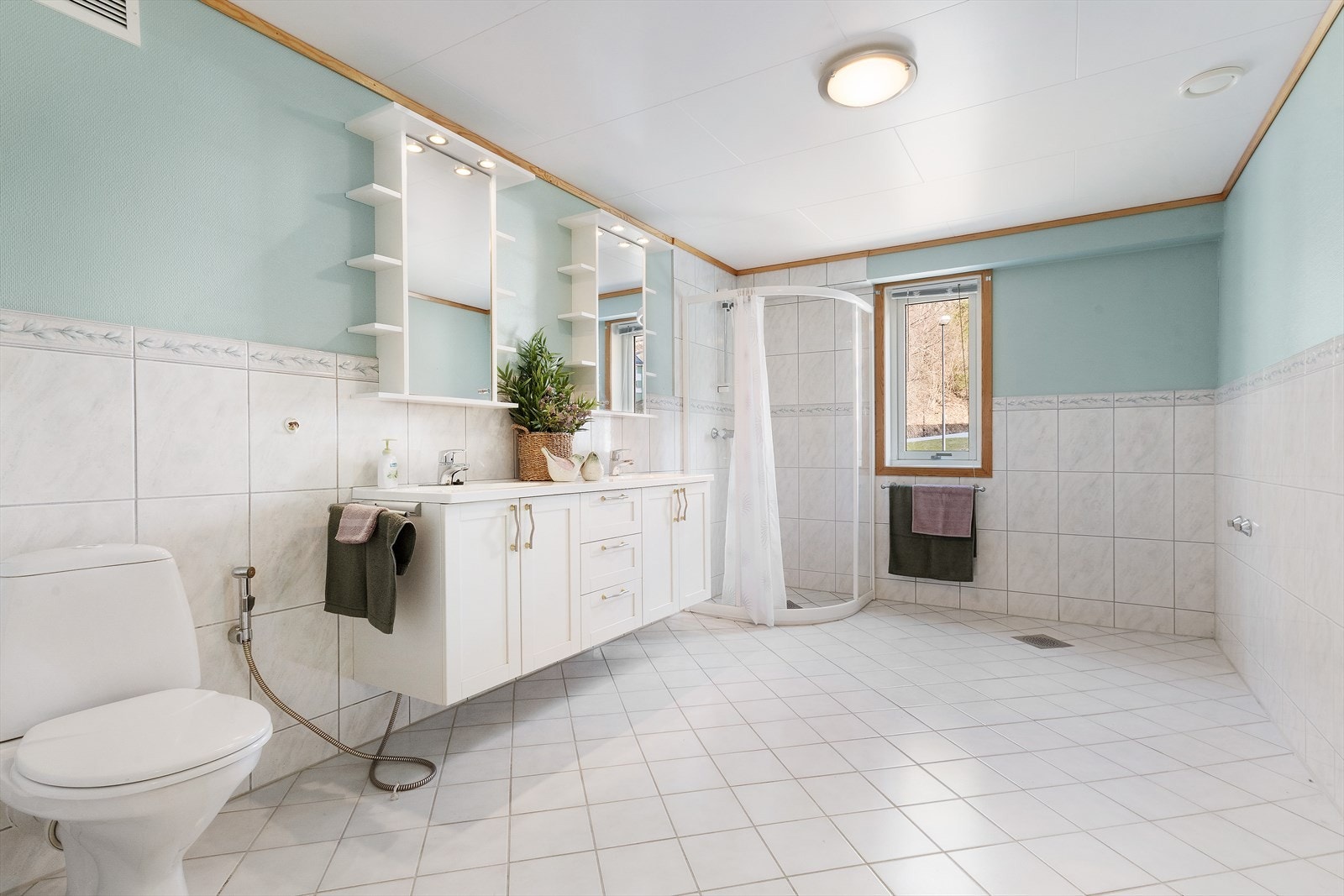 Romslig bad som er innredet med dusjhjørne, toalett og innredning med servant. Det er også opplegg for badekar. Galleribilde