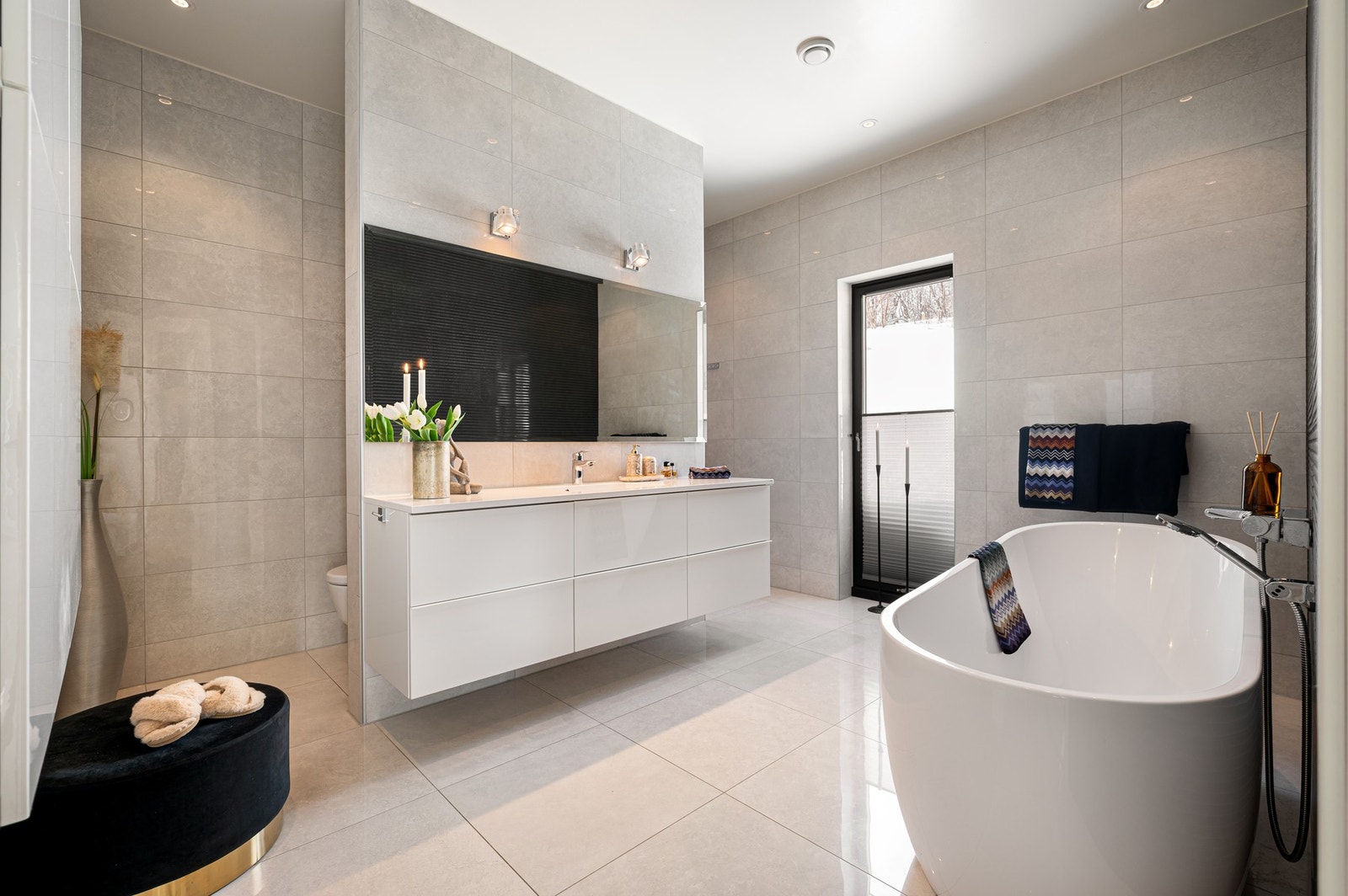 Flislagt bad i delikat og luksuriøs utførelse med badekar og "skjult" toalett og dusj Galleribilde